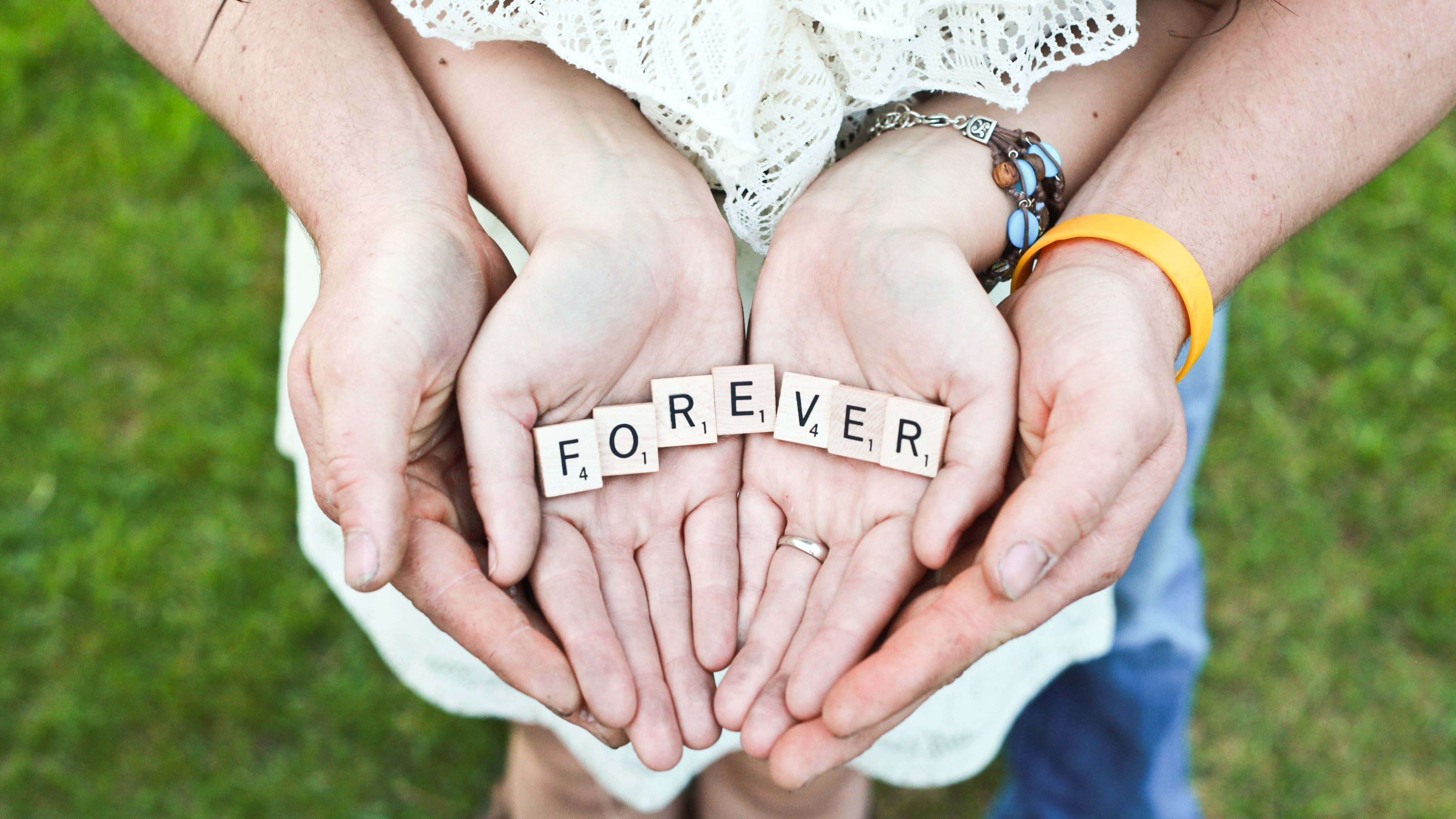 forever 桌布 壁紙 — 兩對手在戶外合在一起，用木字母磚在草地背景上拼出「FOREVER」。