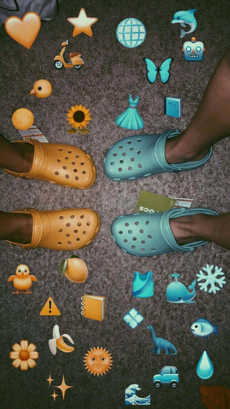 Crocs 桌布 壁紙 — 兩對色彩繽紛的Crocs鞋放在地毯上，周圍散落著表情符號貼紙。