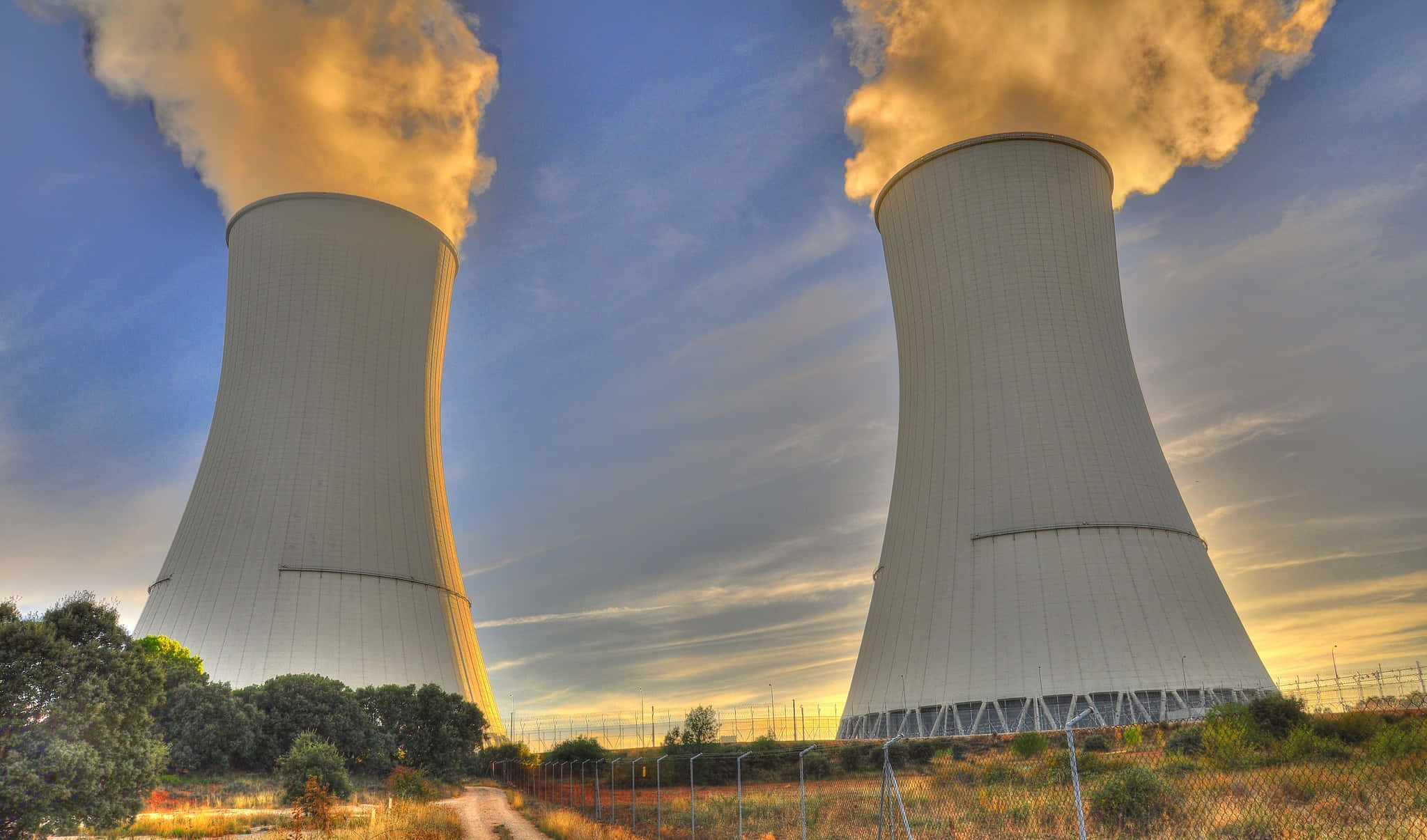 Energy 桌布 壁紙 — 兩座巨大的核冷卻塔在暮色天空和散雲背景下噴出金色蒸汽。
