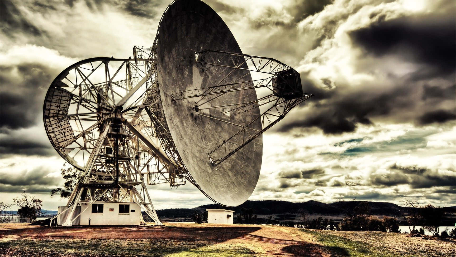 Radio Telescope 桌布 壁紙 — 兩座巨大的無線電望遠鏡在偏遠的景觀中，聳立在戲劇性的多雲天空下。