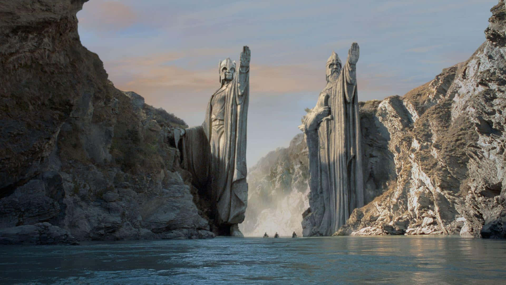 Lotr 桌布 壁紙 — 兩座巨大的石像身穿長袍，在峽谷中守衛，小船在它們下方平靜的水面上漂流。