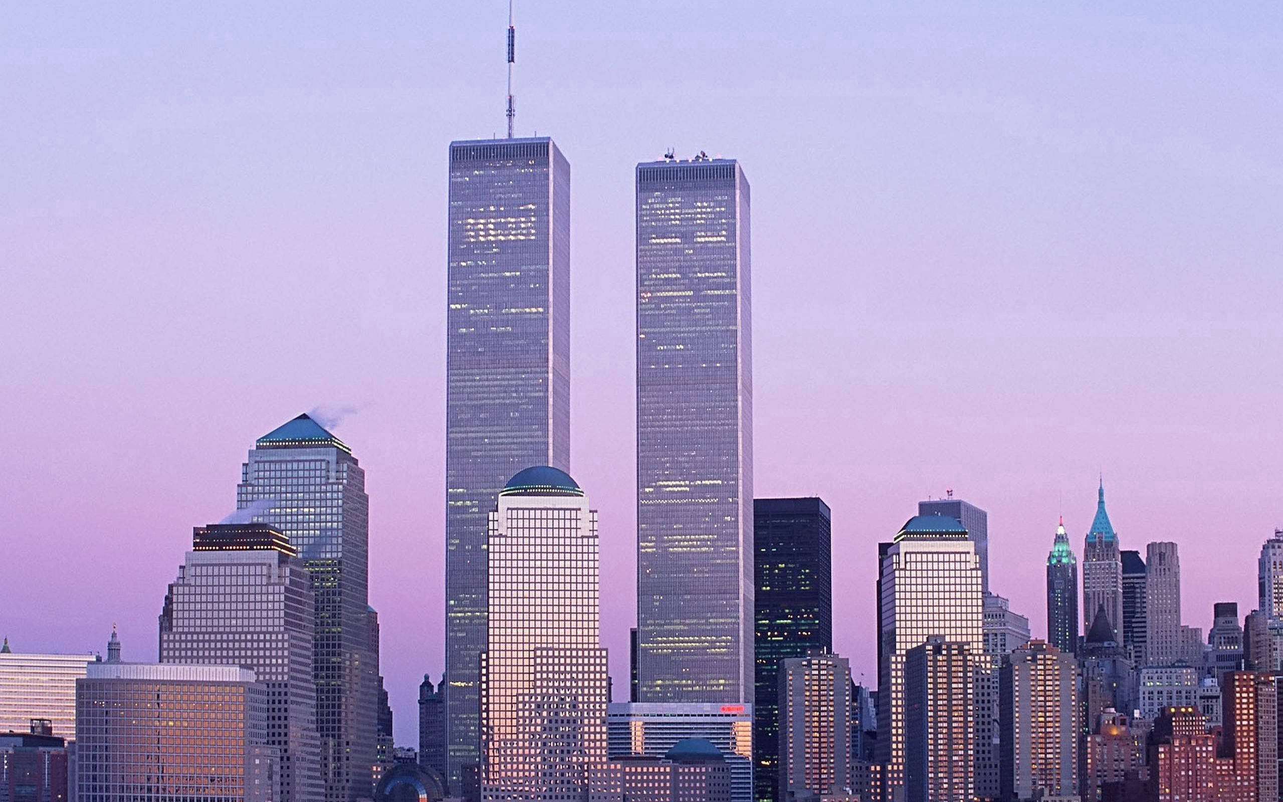 New York 桌布 壁紙 — 兩座標誌性摩天大樓聳立在密集的城市天際線上，沐浴在柔和的紫色暮光中。