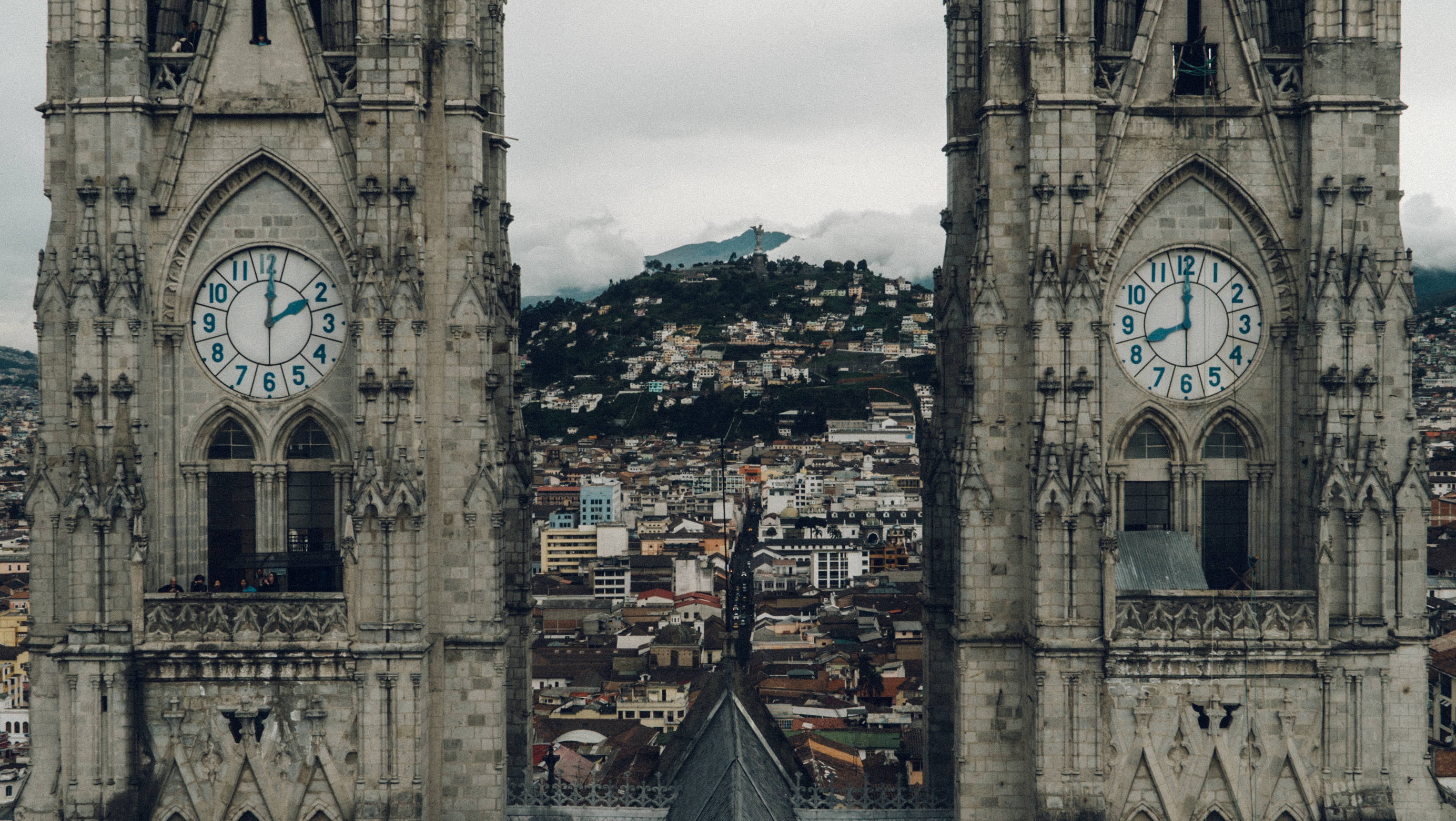 Ecuador 桌布 壁紙 — 兩座華麗的哥德式鐘樓框住了廣闊的城市景觀，坐落在陰天籠罩下的霧氣瀰漫的山丘上。