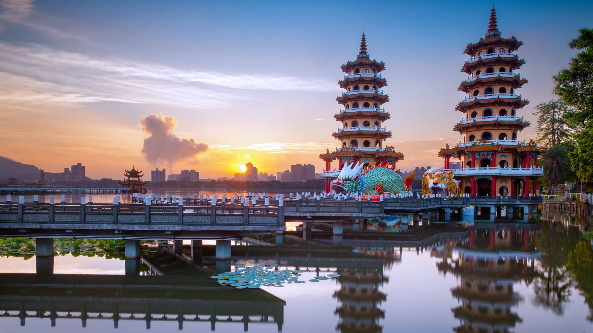 夕陽下兩座寶塔倒映在水中，背景為城市天際線。