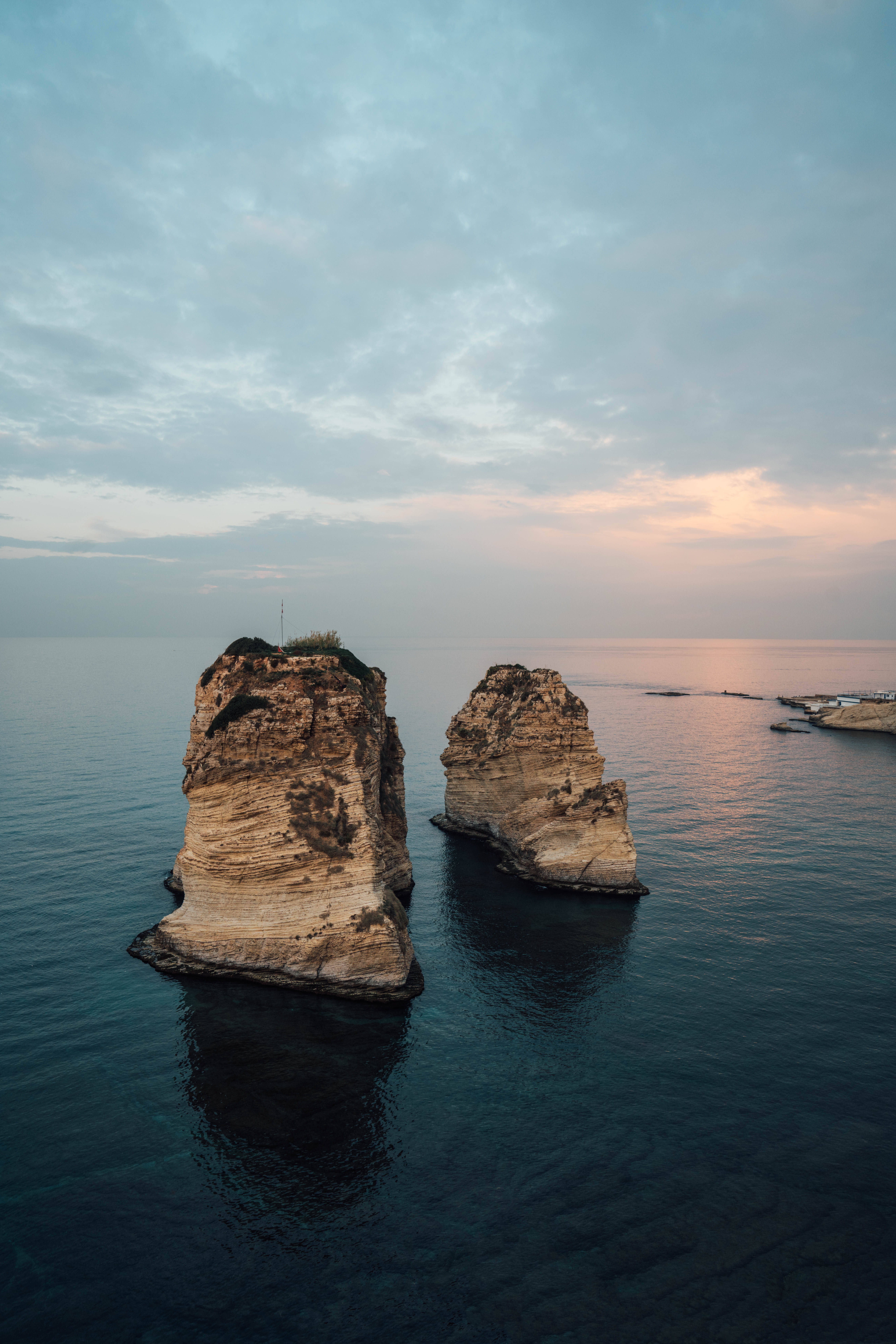 Lebanon 桌布 壁紙 — 兩座高聳的海蝕柱從平靜的海水中升起，在柔和的暮色天空下，伴隨著粉彩色的雲。