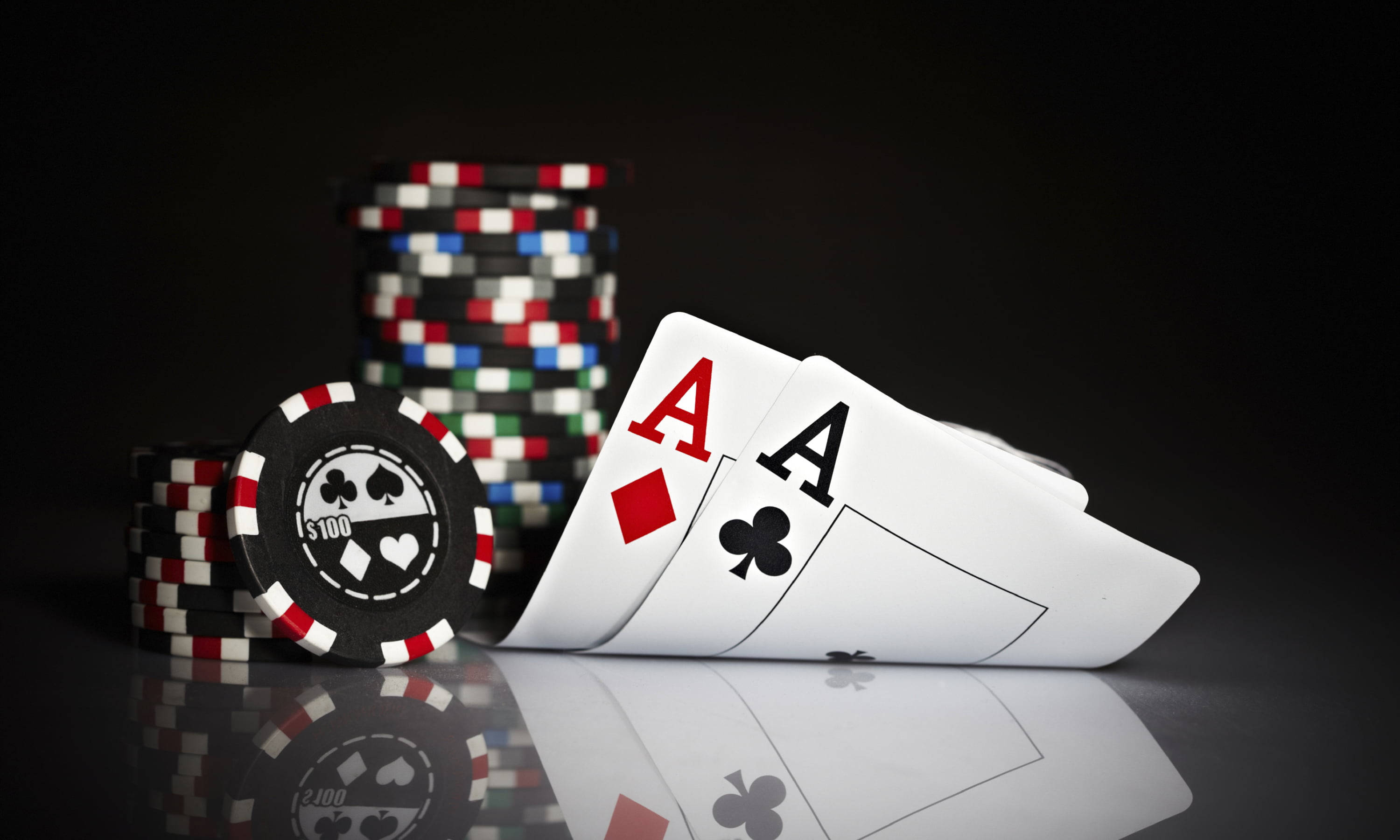 Poker 桌布 壁紙 — 兩張Ace和一堆籌碼在反光黑色表面上閃爍，搭配戲劇性的工作室燈光。
