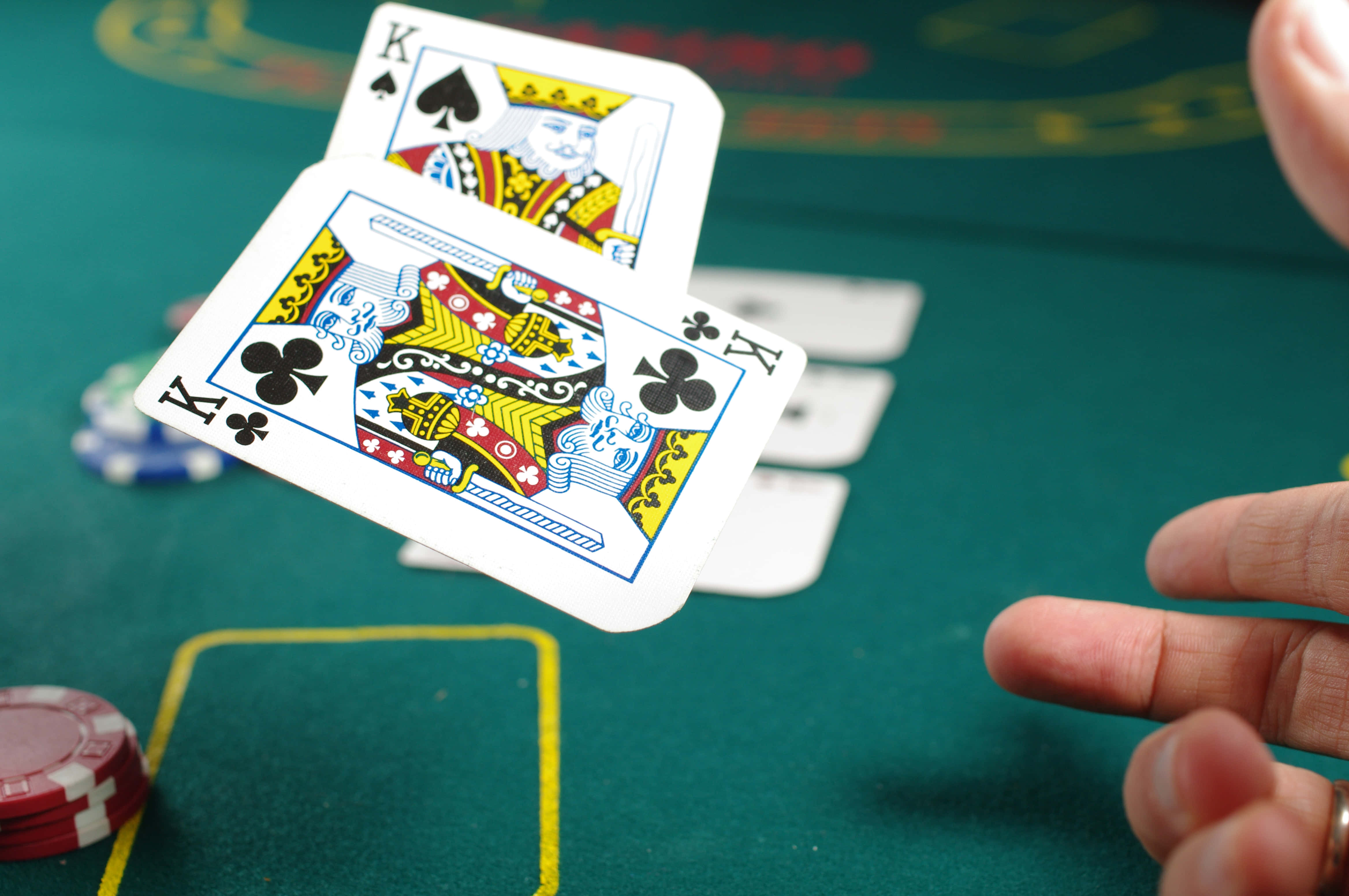 Poker Table 桌布 壁紙 — 兩張國王撲克牌特寫，懸浮在綠色賭桌上，桌上還有籌碼和伸進來的手。