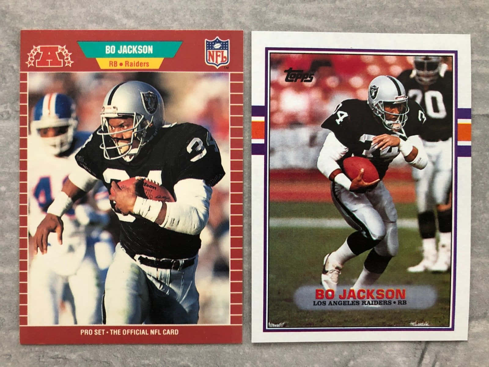 足球 桌布 壁紙 — 兩張復古NFL交易卡，展示穿著Raiders隊服的Bo Jackson在灰色表面上持球奔跑。