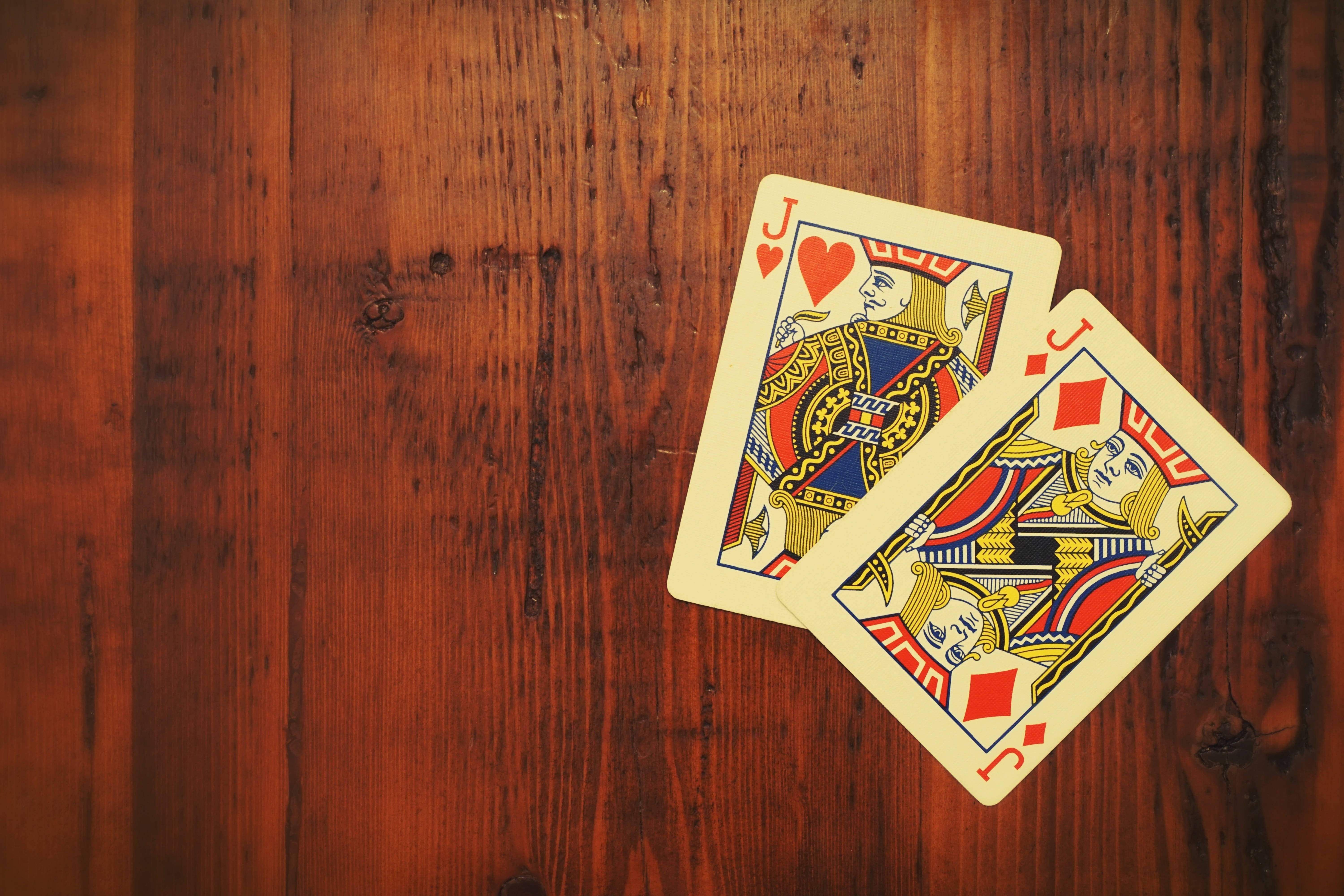 Poker 桌布 壁紙 — 兩張復古撲克牌，紅心傑克和方塊傑克，放在紋理豐富的木質表面上。