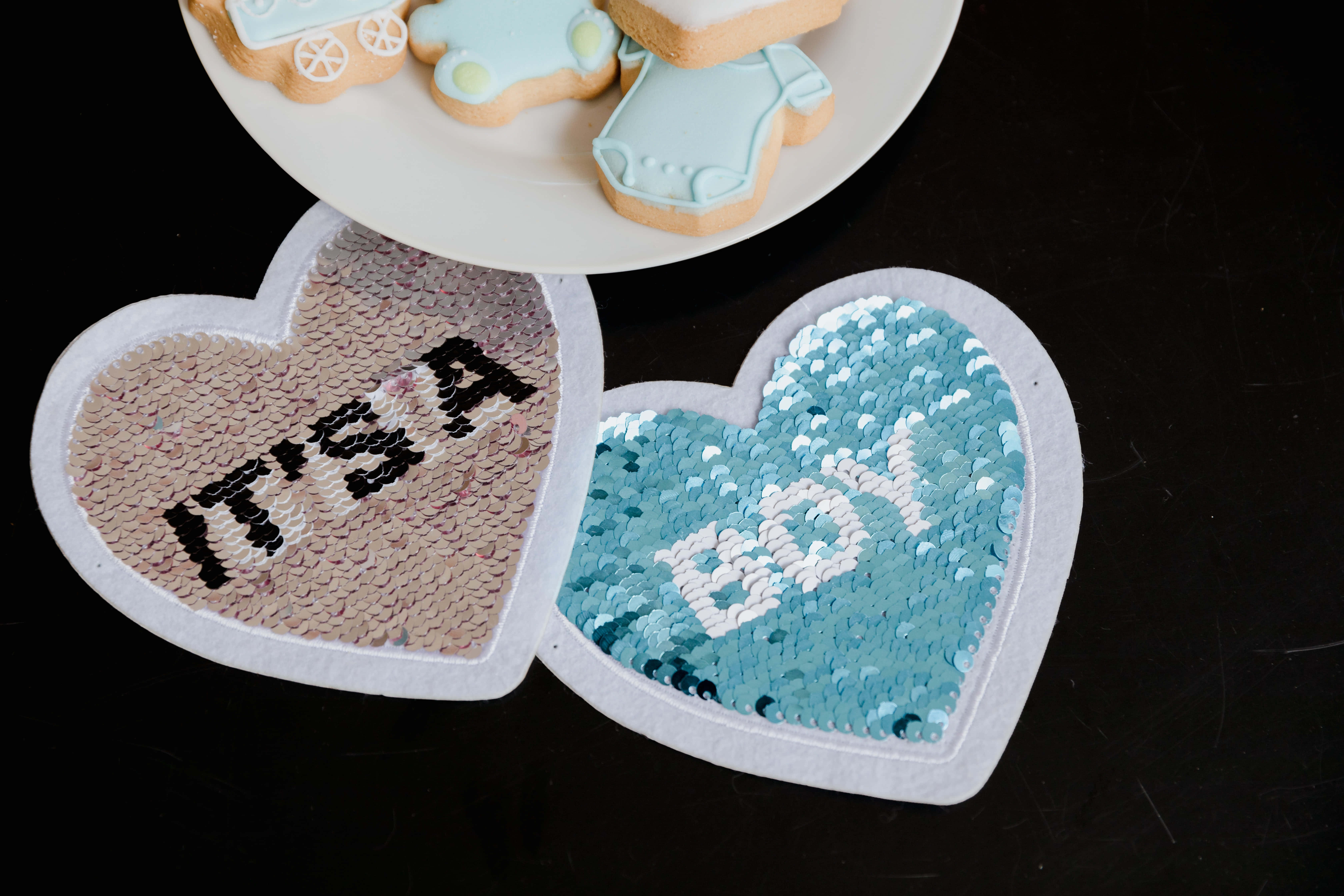 Baby Shower 桌布 壁紙 — 兩張心形亮片卡，用黑白字母拼出「IT'S A BOY」，上方盤子放有嬰兒主題餅乾。
