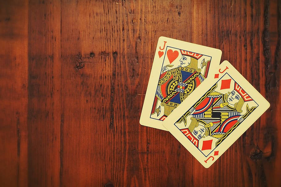Playing Cards 桌布 壁紙 — 兩張撲克牌，紅心傑克和方塊傑克，放在紋理豐富的木質表面上。