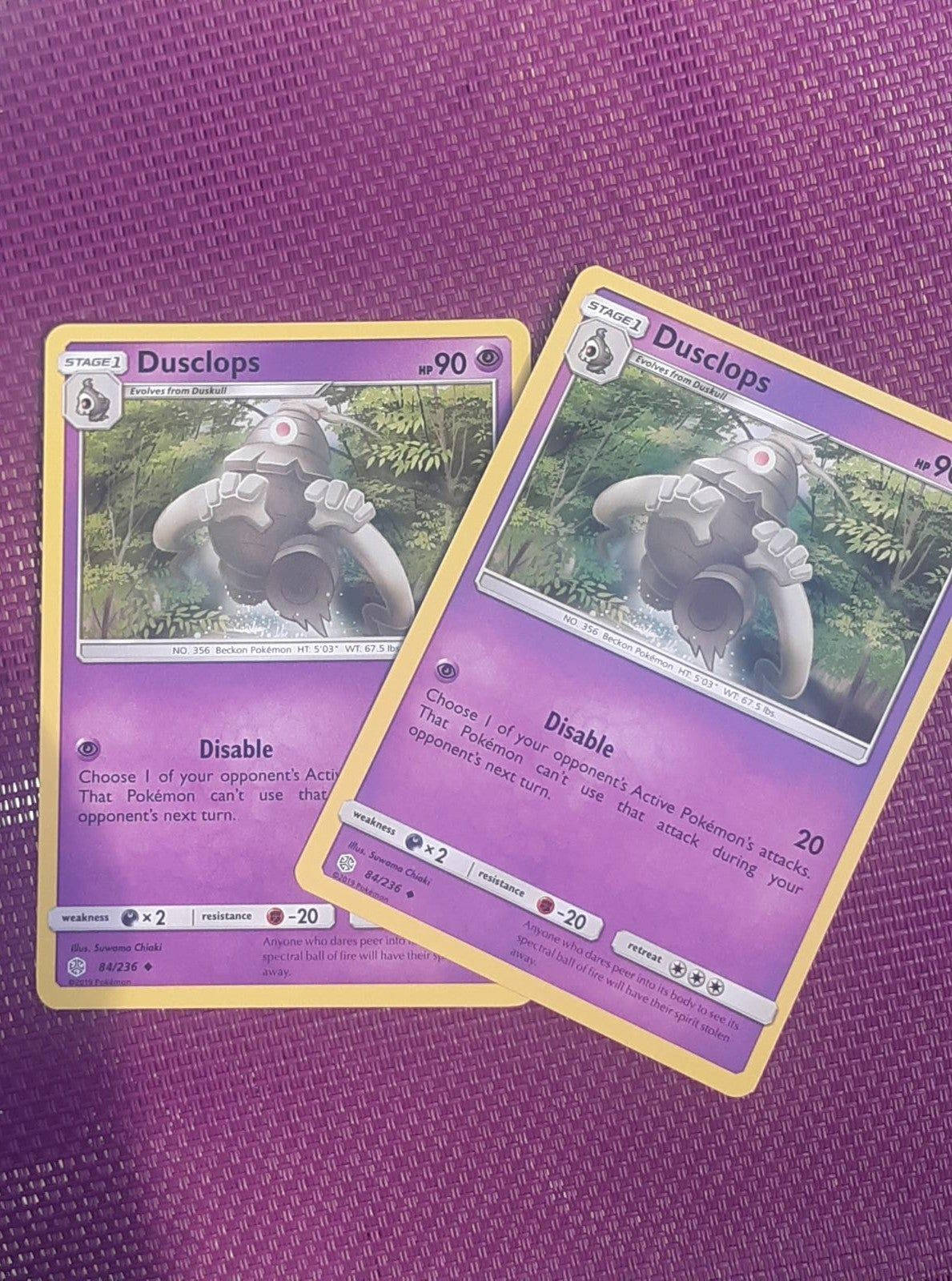 Cards 桌布 壁紙 — 兩張相同的 Dusclops 寶可夢卡重疊放在有紋理的紫色表面上。