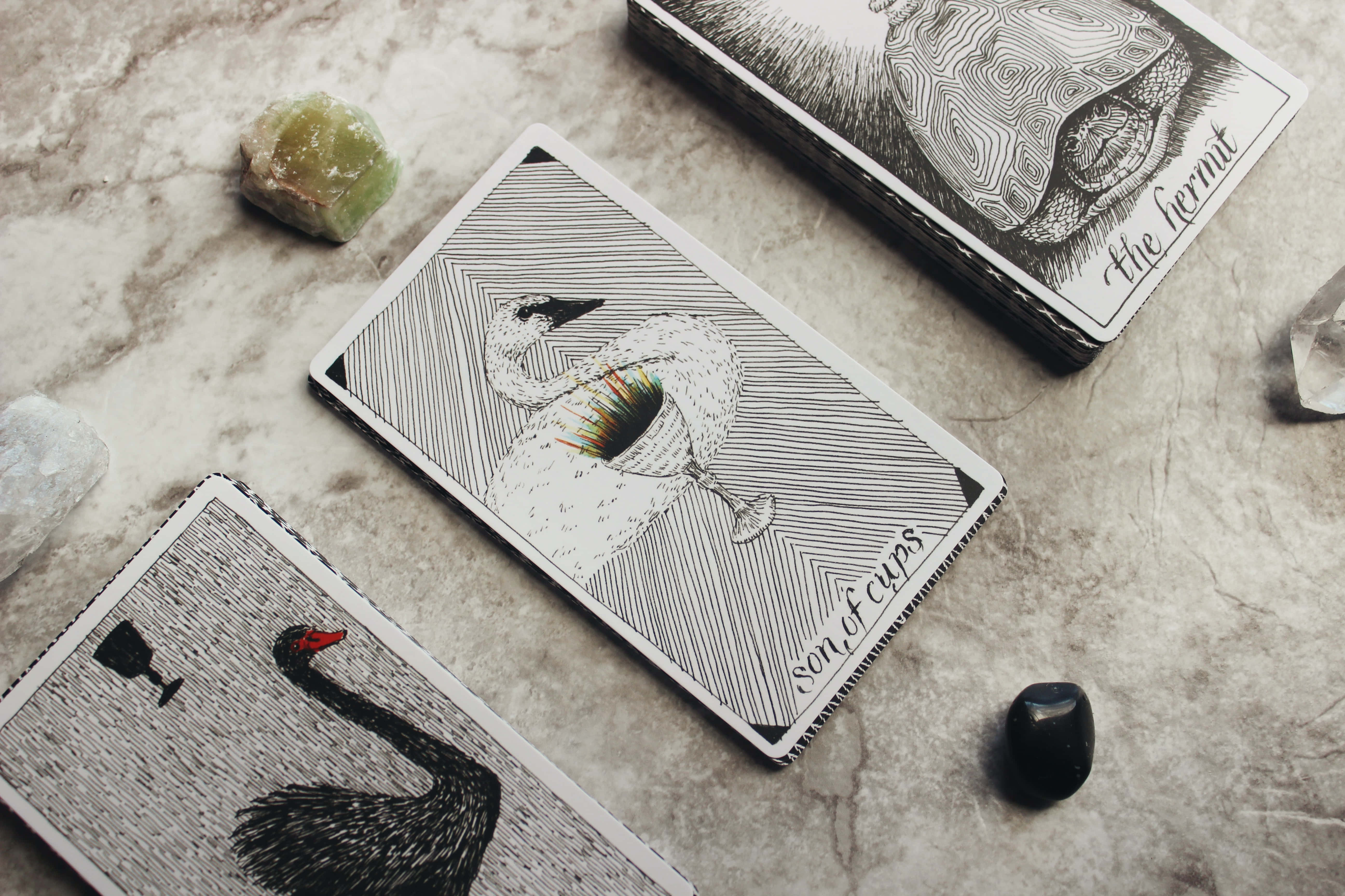Tarot Card 桌布 壁紙 — 兩張精緻插圖的天鵝塔羅牌放在大理石表面上，旁邊有水晶和一副牌。
