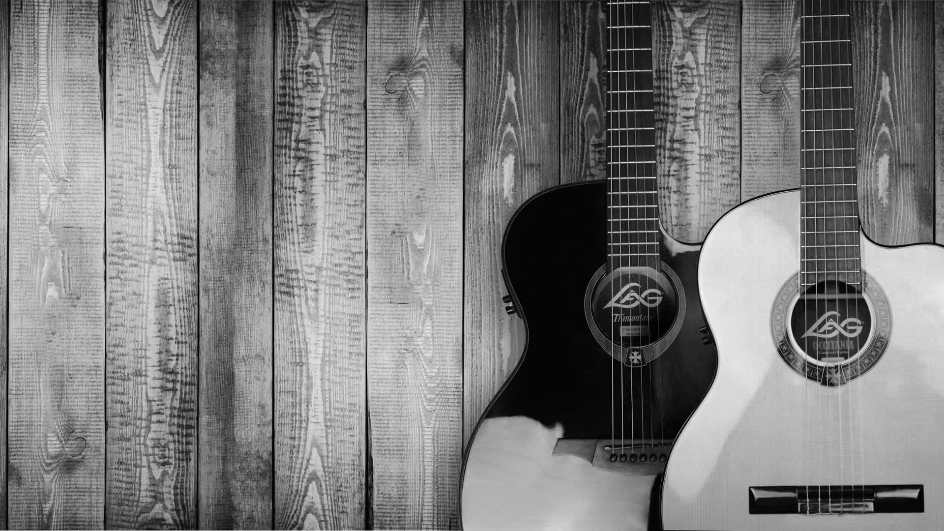 Black And White Guitar 桌布 壁紙 — 兩把原聲吉他，一黑一白，靠在風化的木板上，呈現單色調。