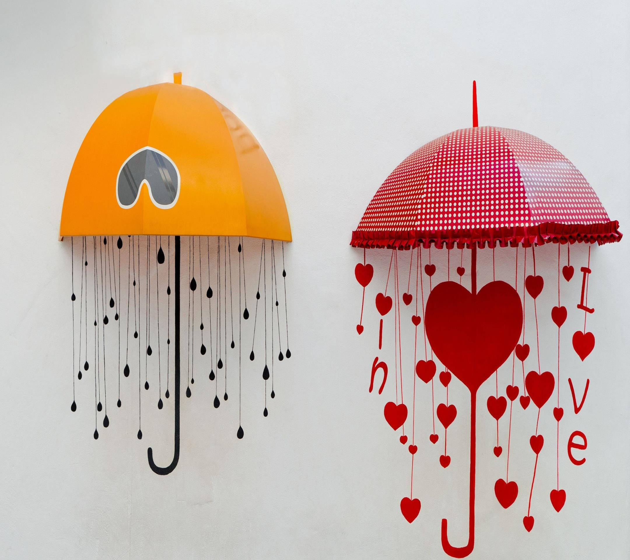 Love Drawings 桌布 壁紙 — 兩把風格化的雨傘，一把橙色帶有心形和黑色雨滴，另一把紅色帶有心形和love字樣，掛在素色牆上。
