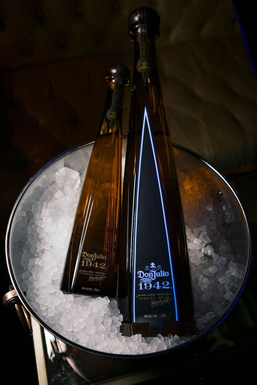 bottle 桌布 壁紙 — 兩支優雅的Don Julio 1942龍舌蘭酒瓶在戲劇性燈光下高高矗立在裝滿碎冰的冰桶中。