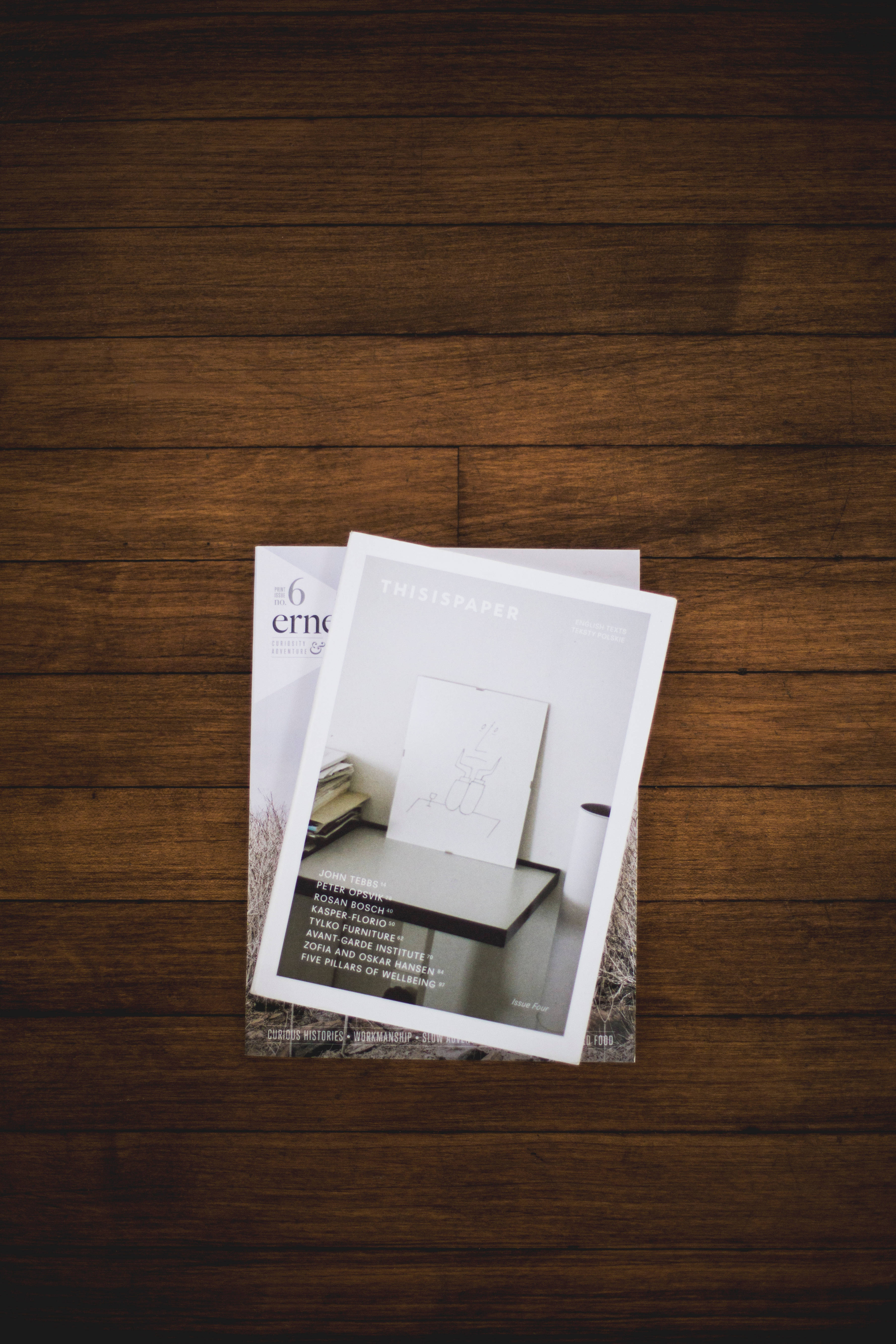 Magazine 桌布 壁紙 — 兩本極簡雜誌放在深色木地板上，溫暖的自然光線照射。