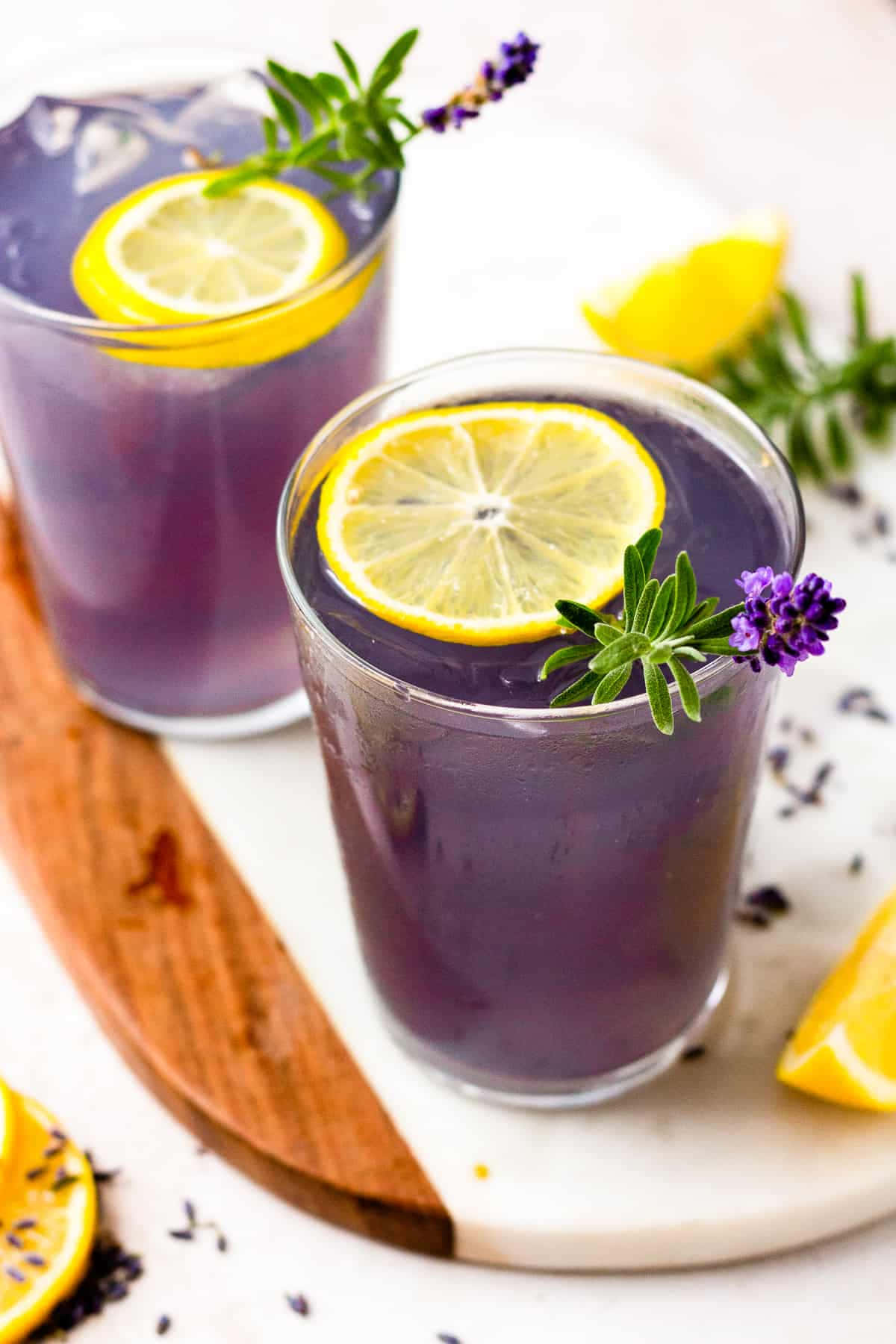 Lemonade 桌布 壁紙 — 兩杯充滿活力的紫色薰衣草檸檬水，飾以檸檬片和新鮮薰衣草枝，放在木質和大理石托盤上。