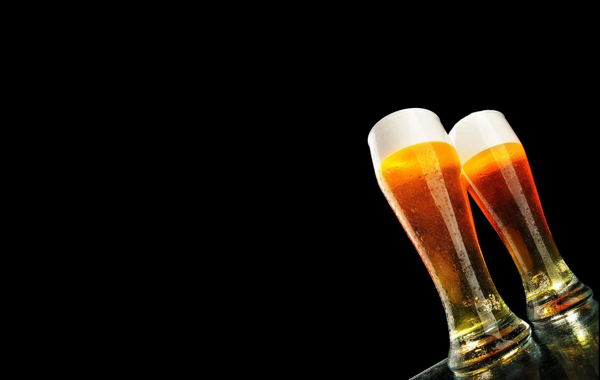 Beer 桌布 壁紙 — 兩杯冰凍琥珀色啤酒杯帶有白色泡沫頭，在純黑背景上互相碰撞。