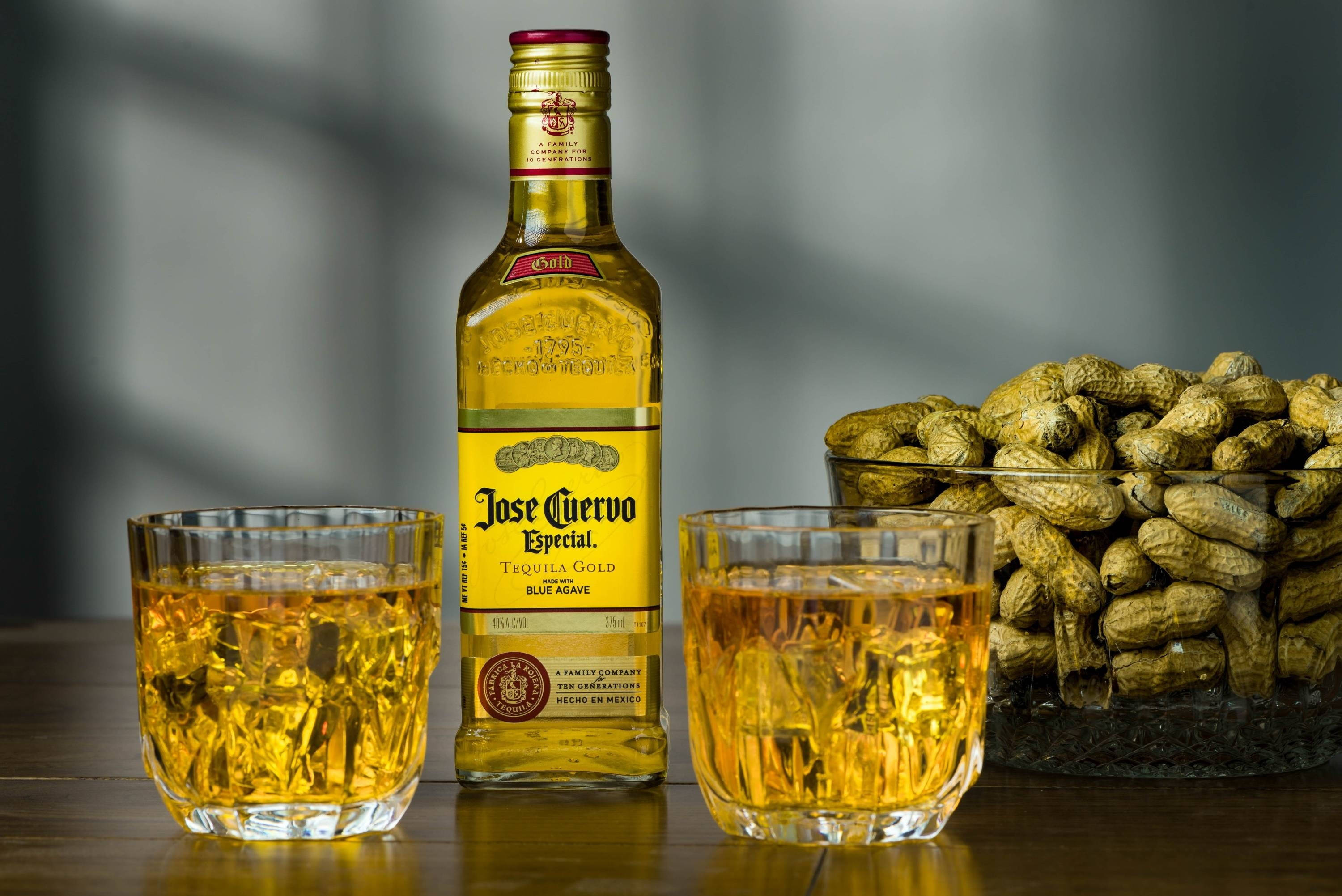 alcohol 桌布 壁紙 — 兩杯加冰龍舌蘭酒放在木桌上，旁邊有一瓶Jose Cuervo Especial Tequila Gold和一碟花生。