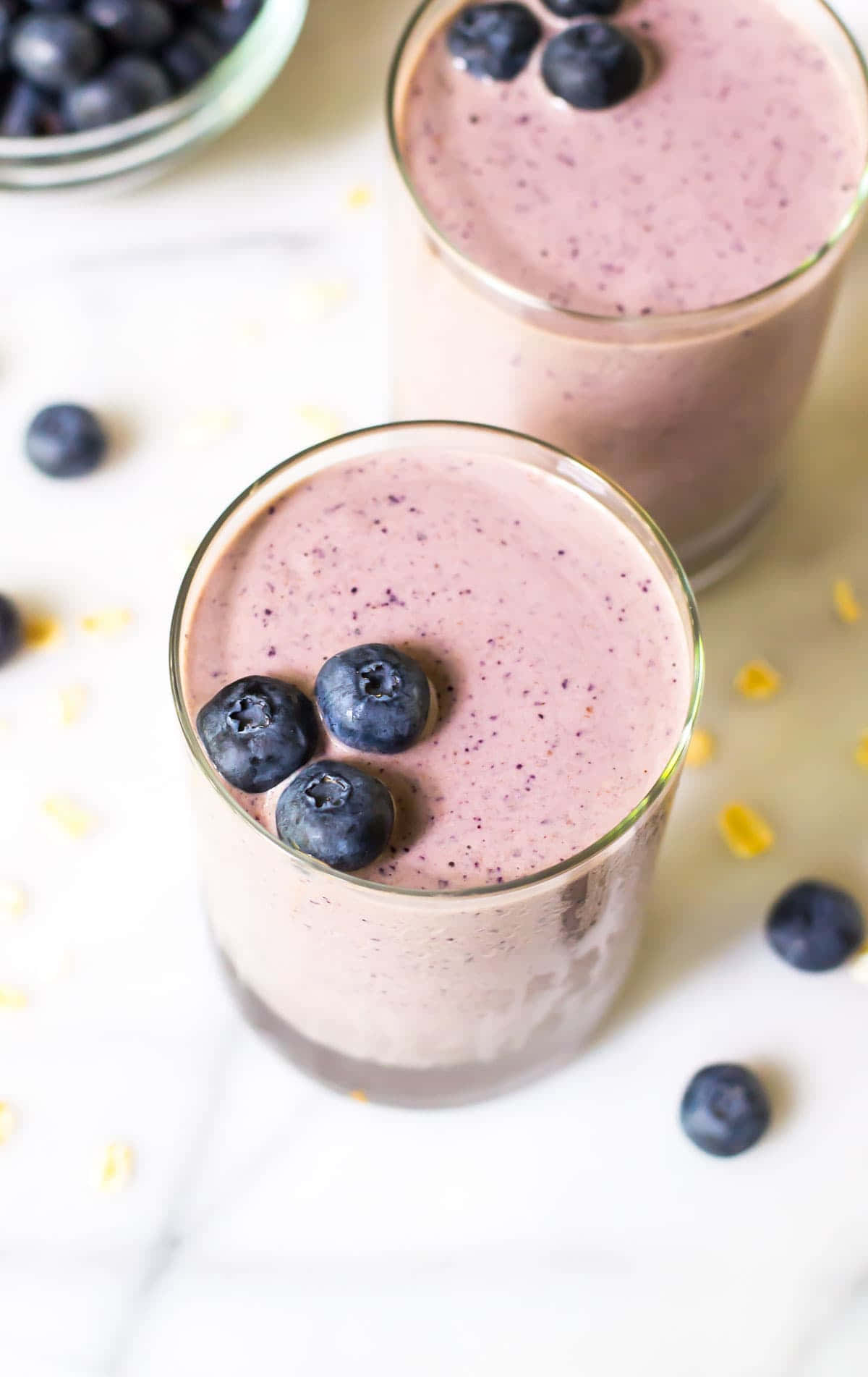 Blueberry Smoothie 桌布 壁紙 — 兩杯奶油般的紫色藍莓奶昔，上面放上新鮮藍莓，置於白色大理石表面上。