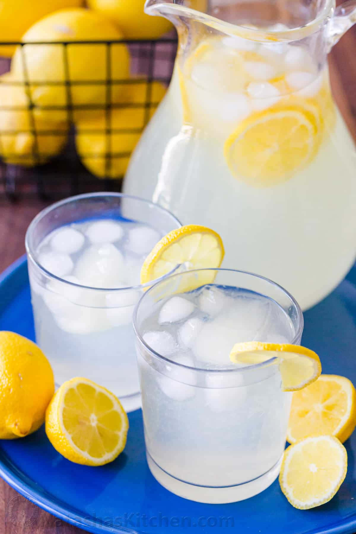Lemonade 桌布 壁紙 — 兩杯檸檬水加冰和檸檬片放在藍色托盤上，旁邊有一個壺和新鮮檸檬。