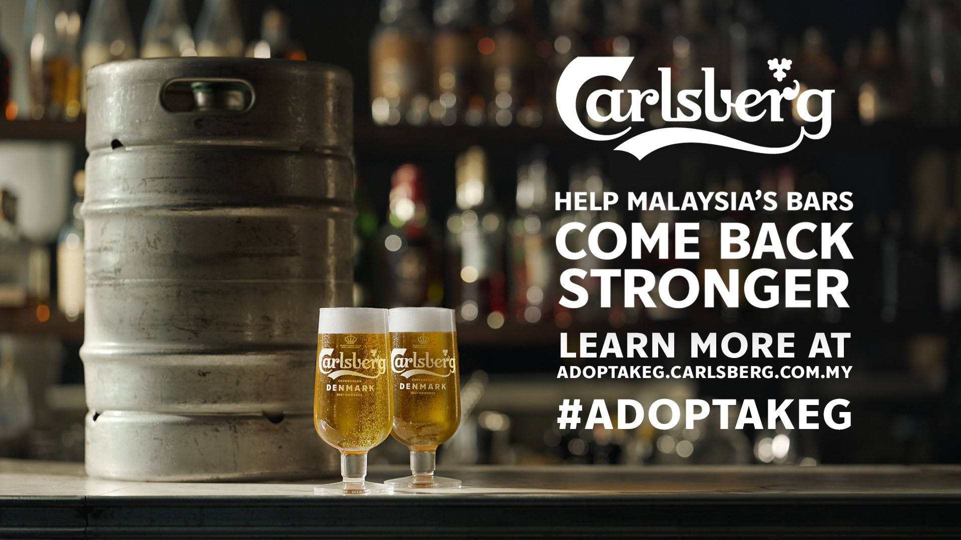 Beer 桌布 壁紙 — 兩杯泡沫豐富的嘉士伯啤酒放在吧檯上的一個酒桶旁邊，背景是模糊的酒瓶。