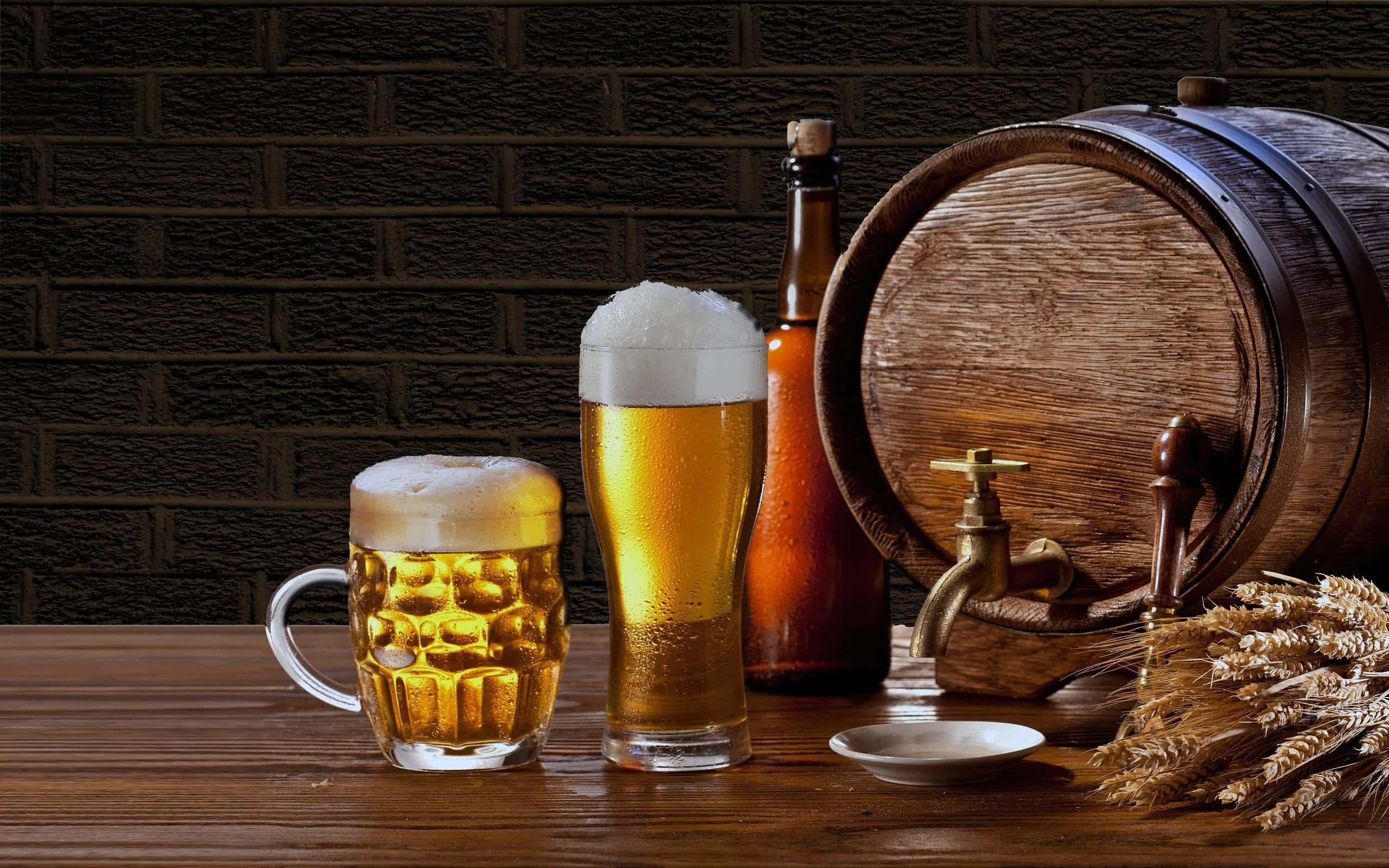 Beer 桌布 壁紙 — 兩杯泡沫金黃啤酒放在木桶和小麥稈旁邊，置於質樸的木桌上，背景是深色磚牆。