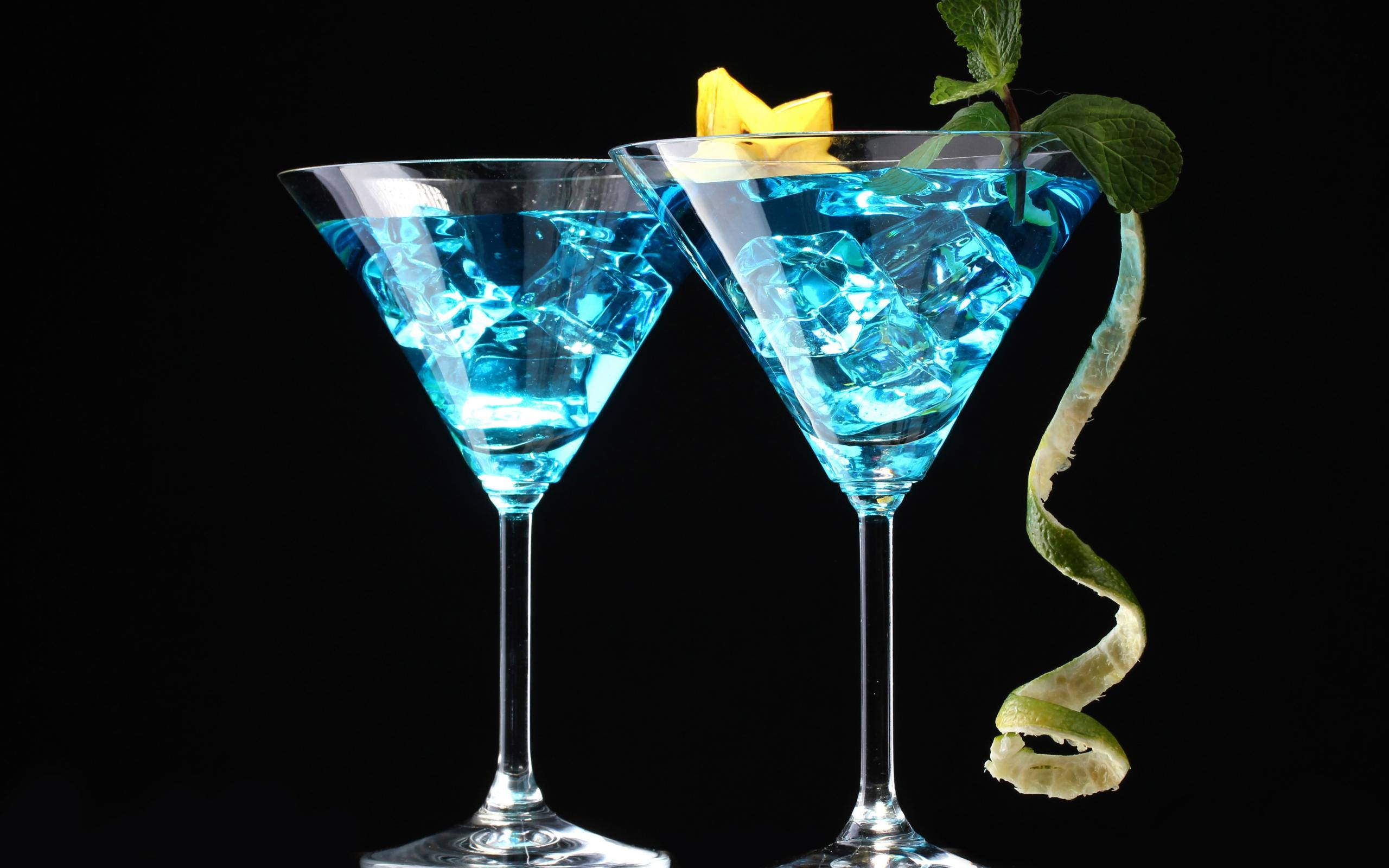 Drink 桌布 壁紙 — 兩杯發光的藍色雞尾酒盛載於馬丁尼杯中，飾以薄荷和柑橘，背景為黑色。