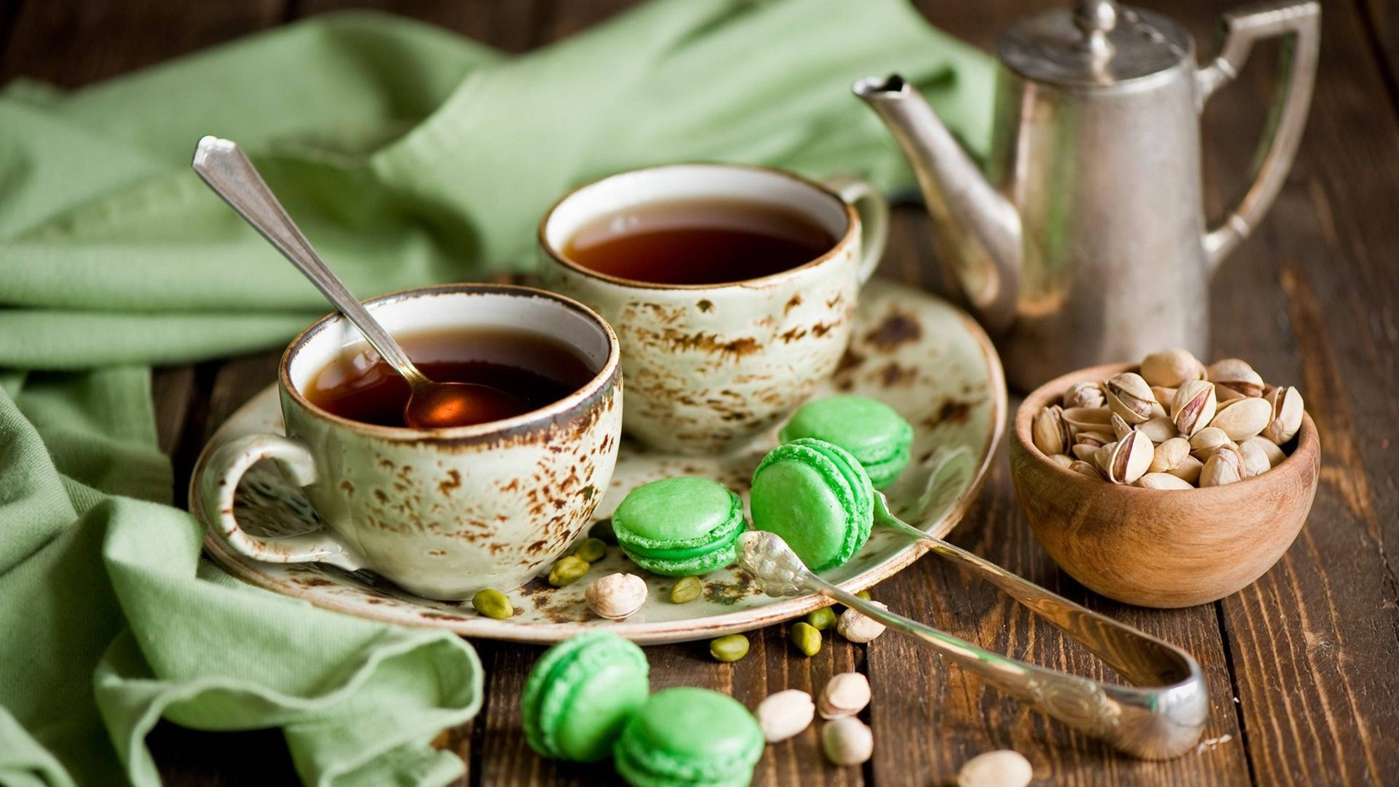 tea 桌布 壁紙 — 兩杯鄉村風格的茶，搭配綠色馬卡龍和開心果，放在鋪有綠色布的桌子上。