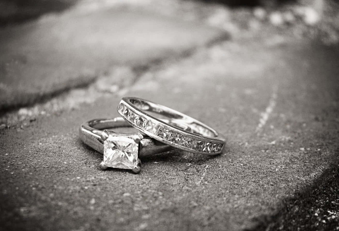 結婚戒指 桌布 壁紙 — 兩枚優雅的鑽石戒指放置在紋理石面上，構成單色畫面。