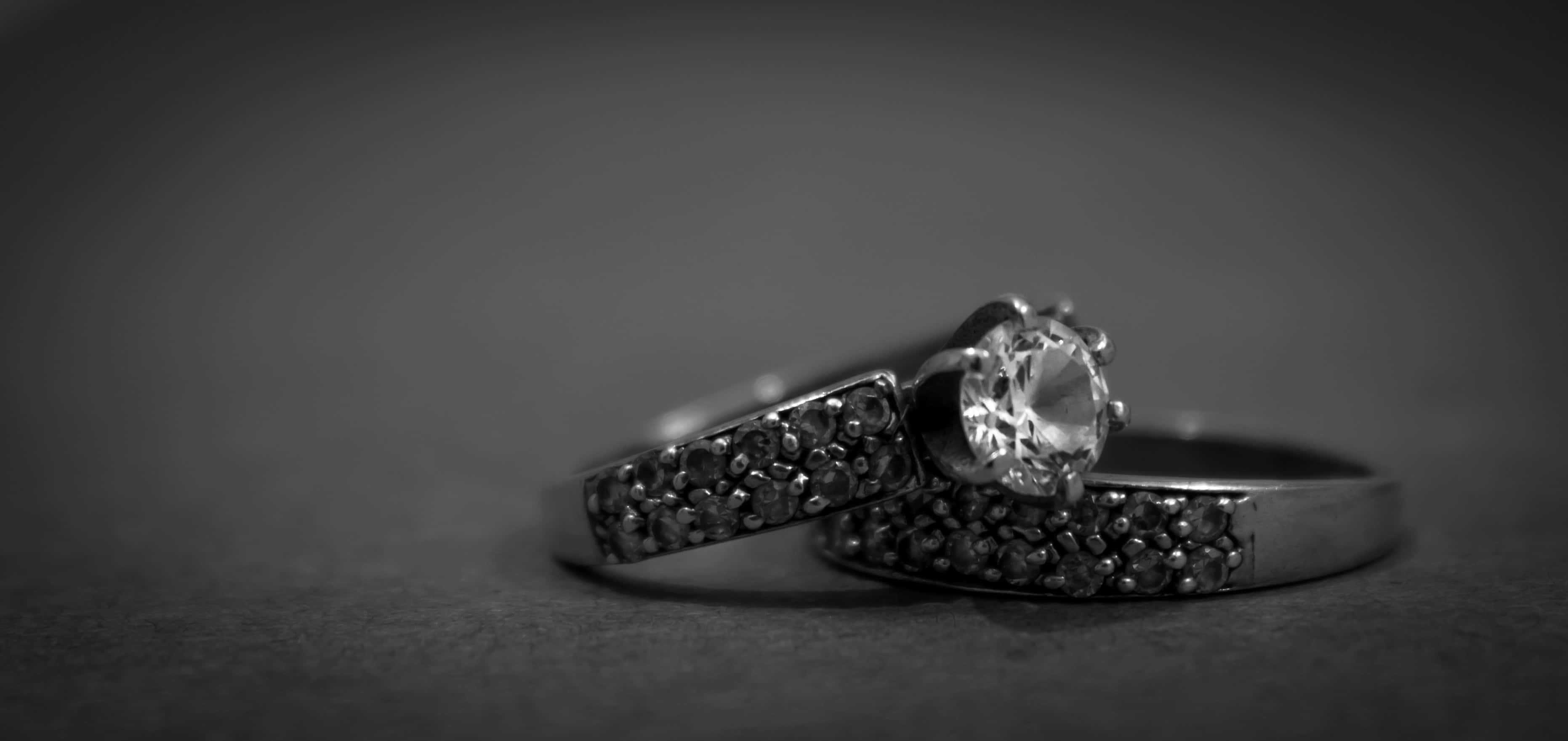 Wedding Rings 桌布 壁紙 — 兩枚優雅的黑白鑽石戒指一起放在柔軟的紋理表面上，構成憂鬱的單色構圖。