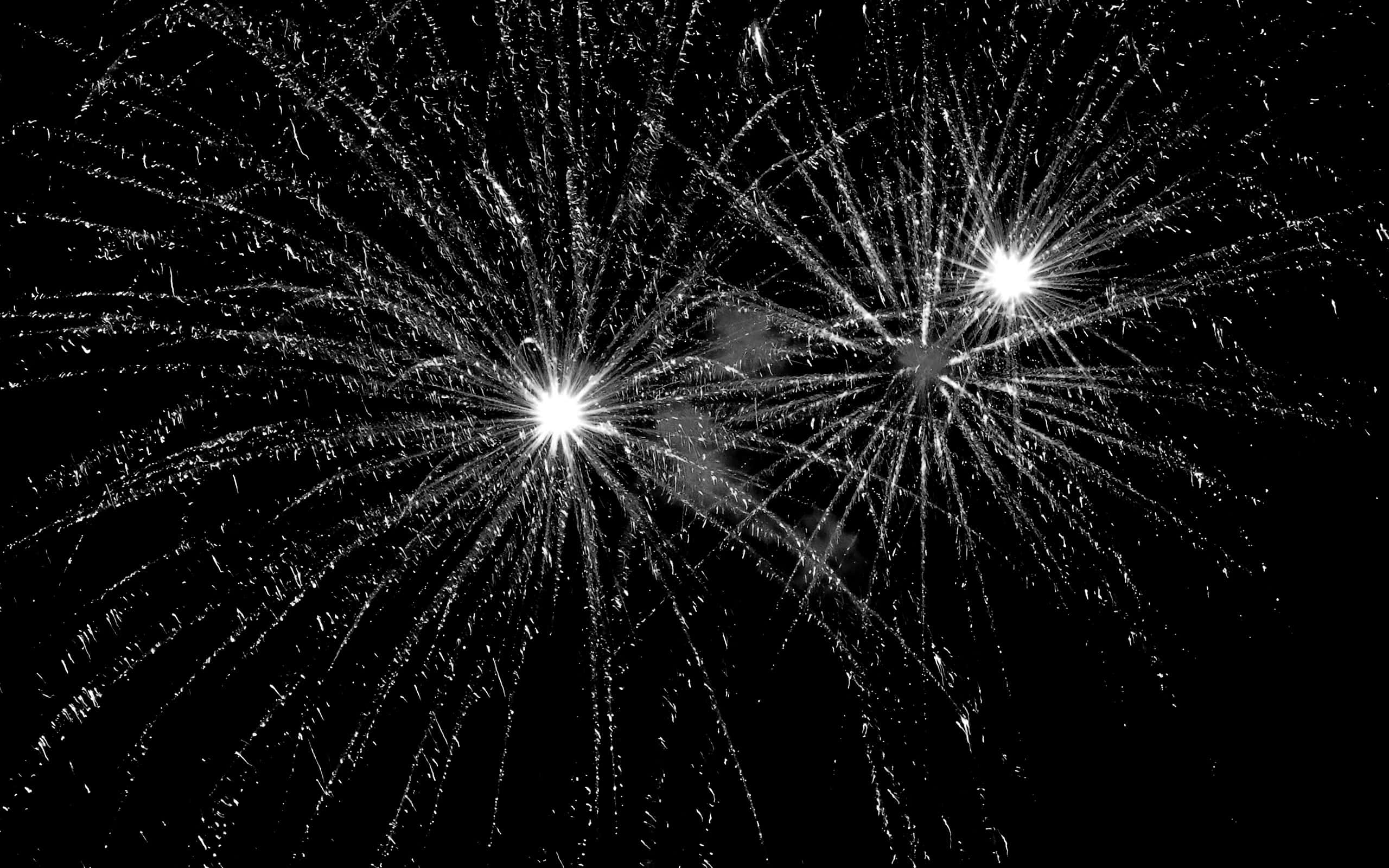 firework 桌布 壁紙 — 兩枚璀璨煙火在漆黑夜空下以強烈黑白對比爆炸，放射出明亮條紋。