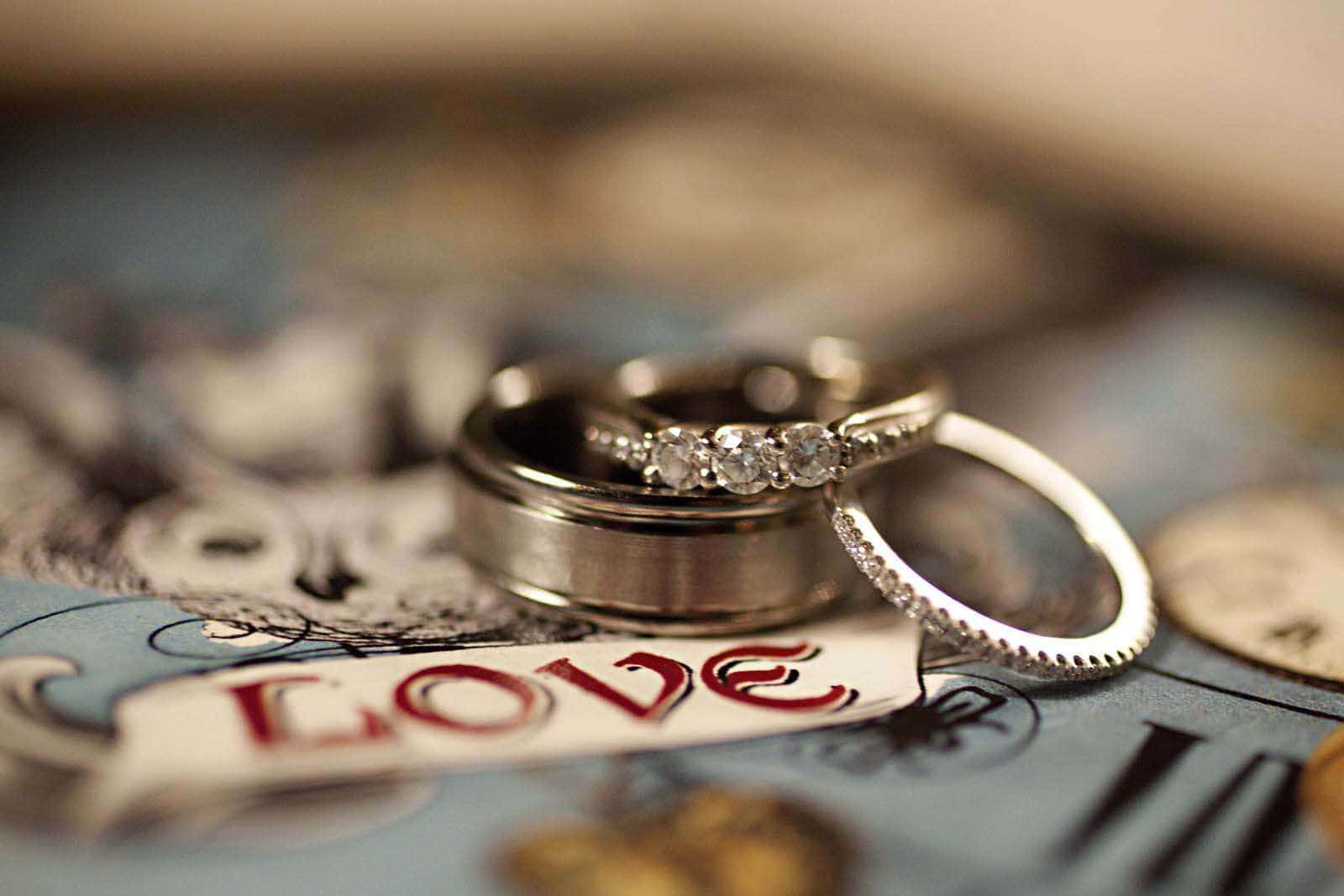 Wedding Rings 桌布 壁紙 — 兩枚結婚戒指在復古地圖上閃耀，上面有紅色字體的love字樣。