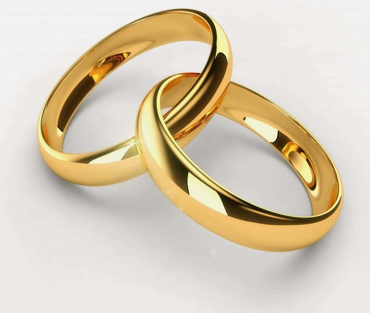 Wedding Rings 桌布 壁紙 — 兩枚閃閃發光的金色結婚戒指在柔軟的白色表面上交織，以拋光優雅反射光線。