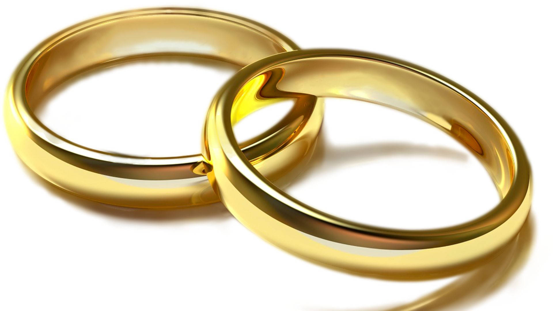 高清 桌布 壁紙 — 兩枚閃閃發光的金色結婚戒指在純白背景上交織，帶有柔和陰影。
