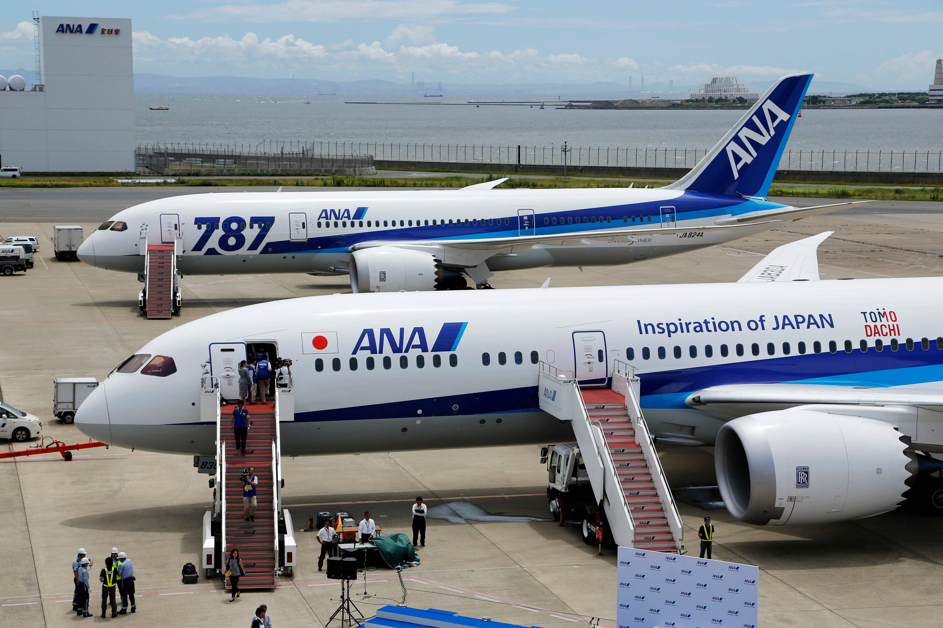 日本 桌布 壁紙 — 兩架ANA波音787夢想客機停泊在機場停機坪，乘客在部分多雲的天空下通過樓梯登機。