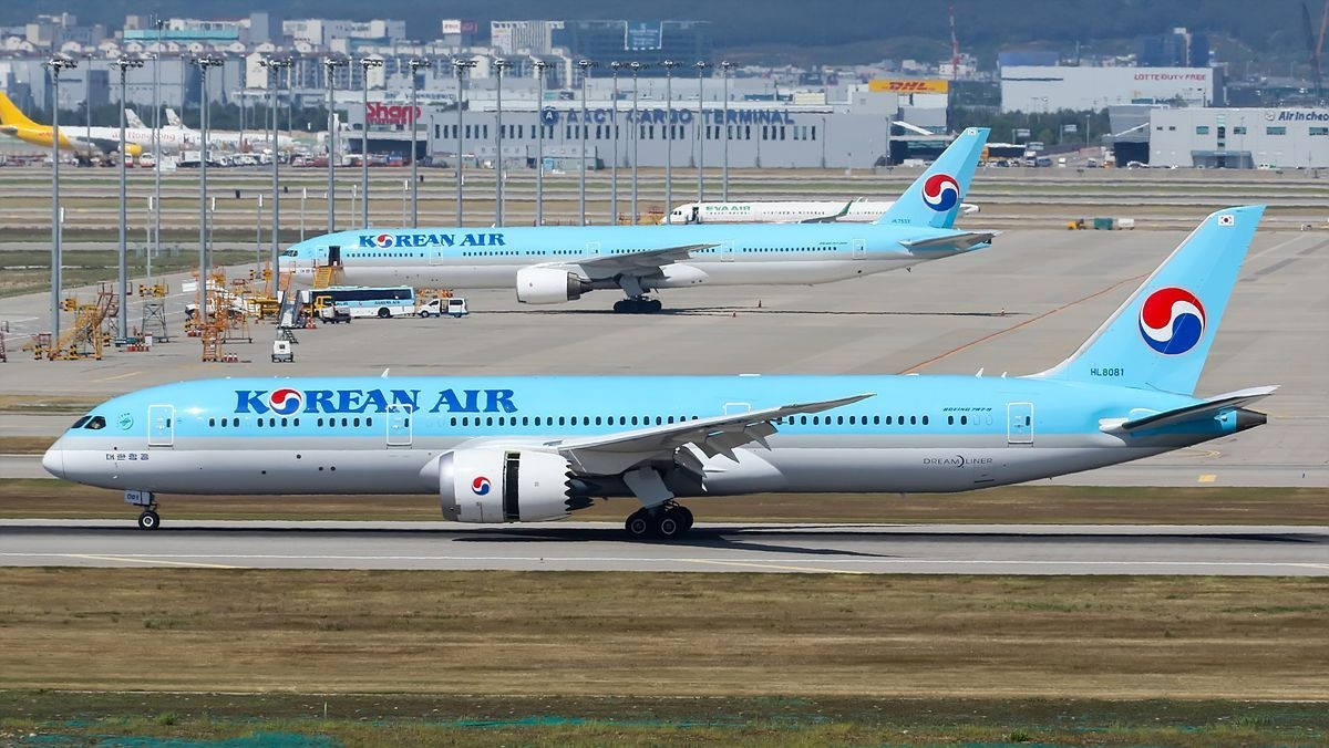 飛機 桌布 壁紙 — 兩架大韓航空波音787夢幻客機在陽光明媚的機場停機坪上滑行，背景有航站樓和地面設備。