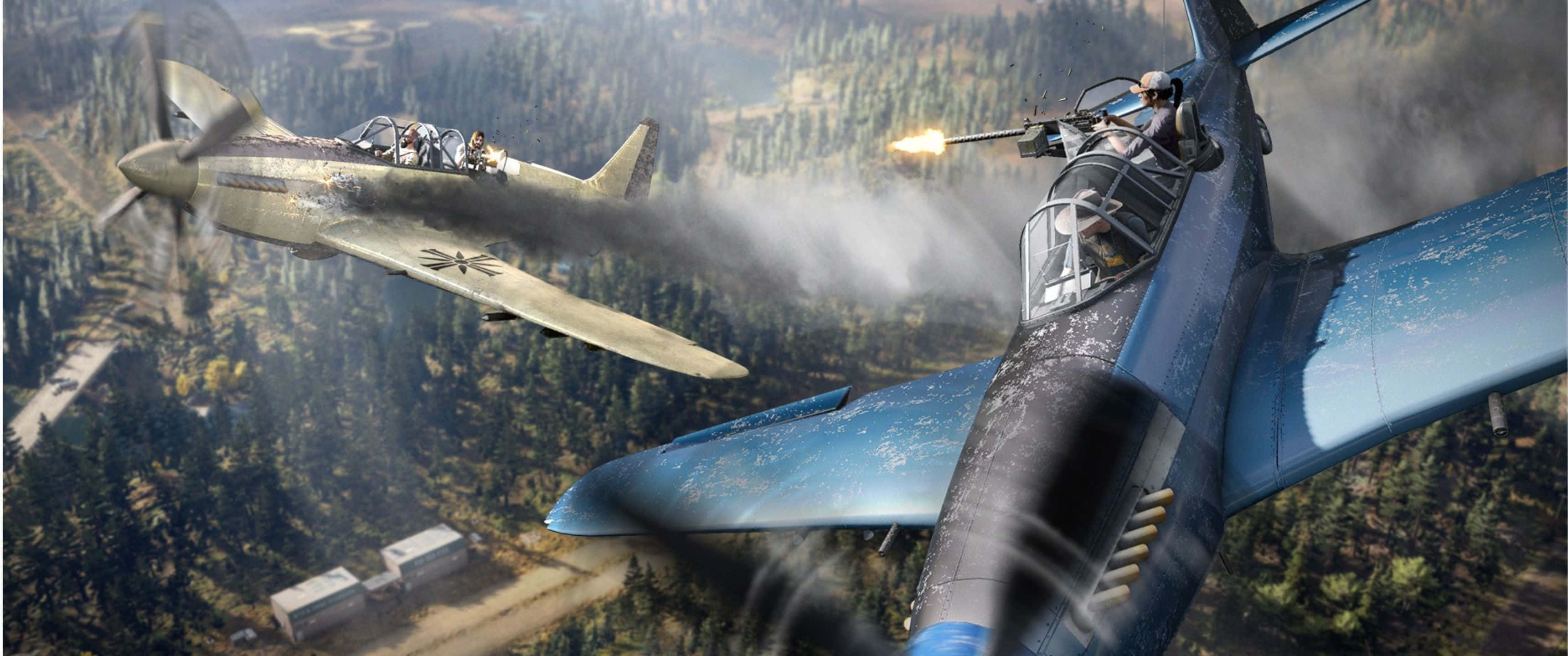 3440x1440p Far Cry 5 桌布 壁紙 — 兩架戰鬥機在森林覆蓋的山谷上空進行纏鬥，其中一架向另一架開火。