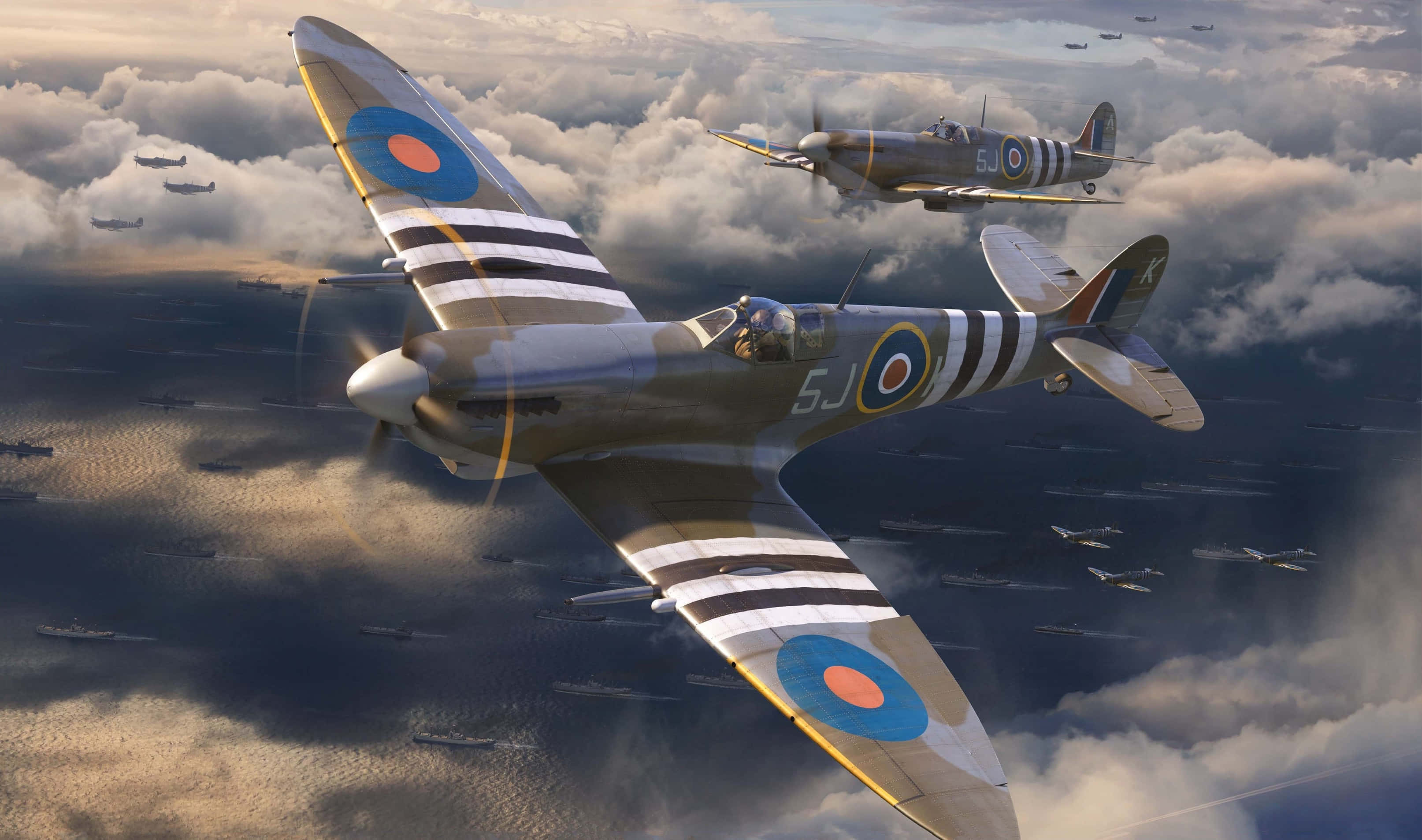 Spitfire 桌布 壁紙 — 兩架標誌性的噴火戰鬥機在波濤洶湧的海面上，穿過戲劇性的雲層，翱翔於軍艦艦隊之上。
