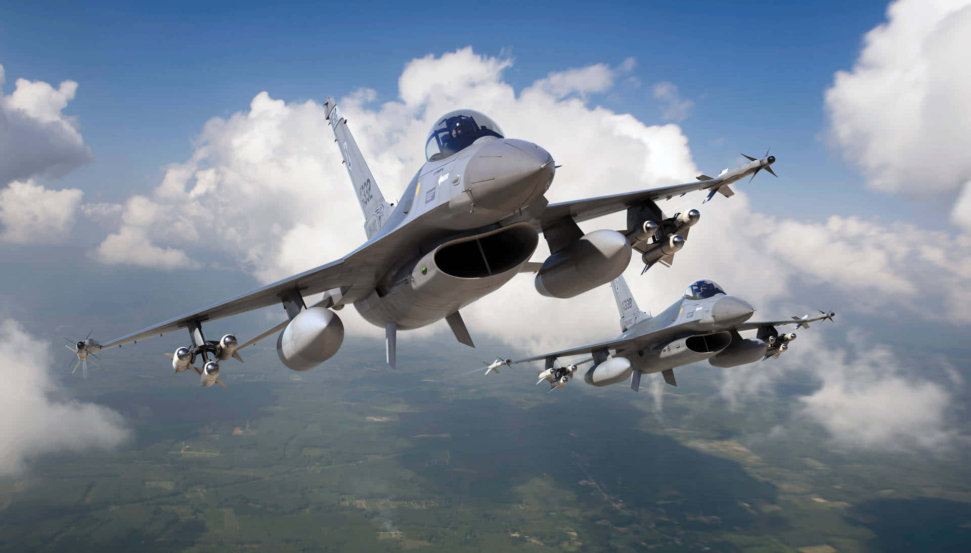 Air Force 桌布 壁紙 — 兩架灰色戰鬥機在明亮的藍天中翱翔，伴隨著蓬鬆的白雲，下方是綠色拼布般的景觀。
