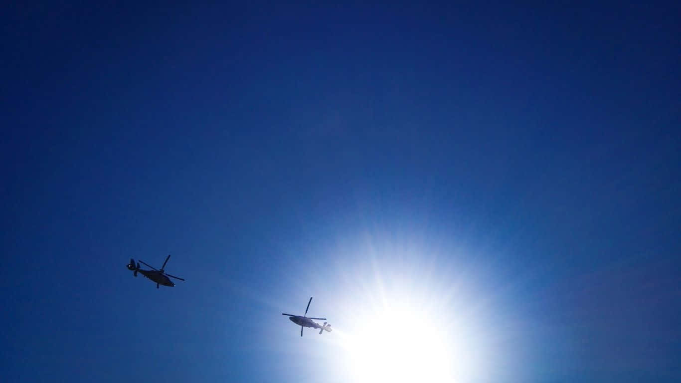 1366x768 Helicopters 桌布 壁紙 — 兩架直升機在明亮的太陽和深藍色天空的襯托下以剪影飛行。