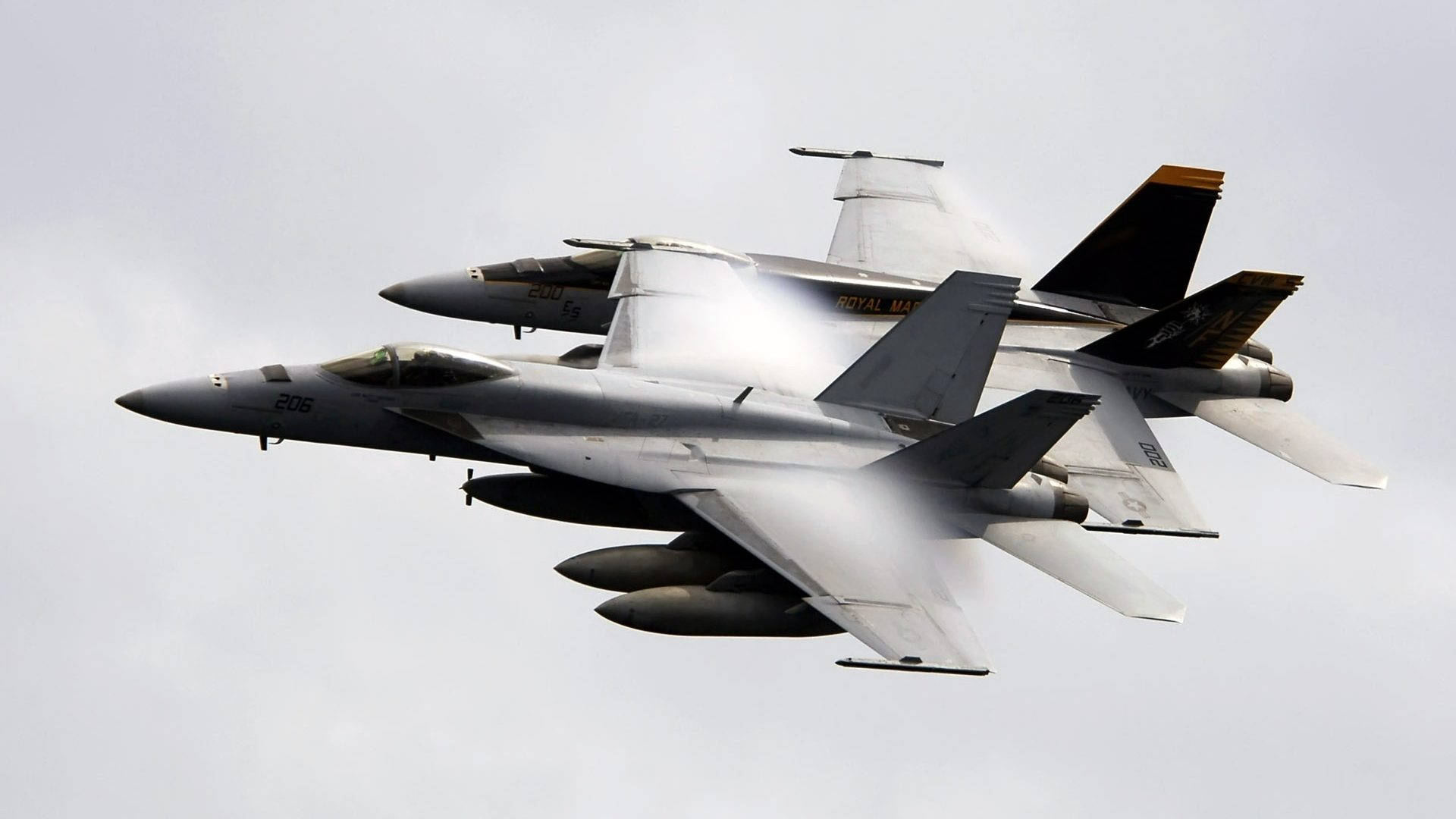 Jets 桌布 壁紙 — 兩架英國皇家海軍戰鬥機在蒼白的陰天緊密編隊飛行，留下蒸汽痕跡。