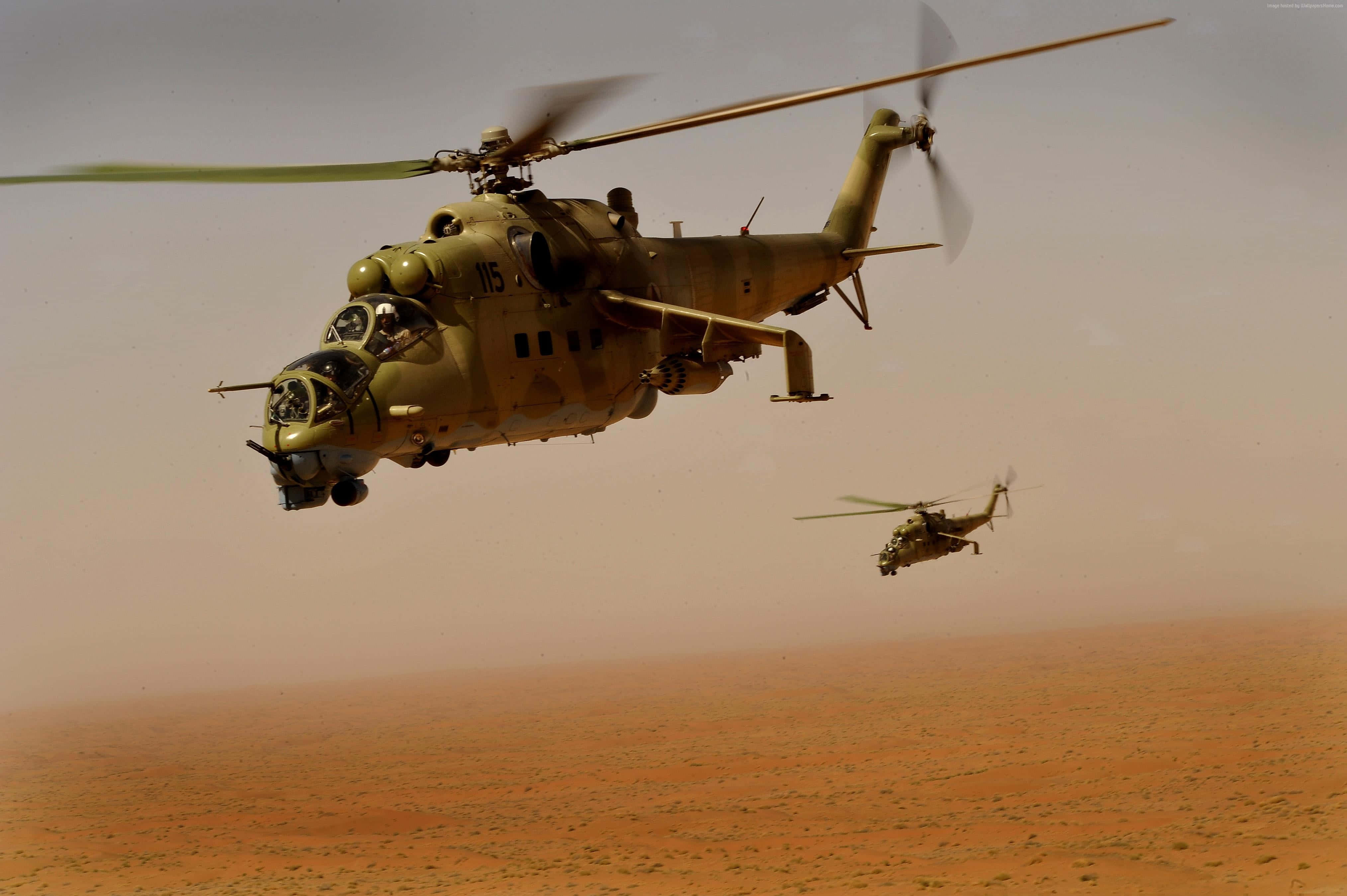 4K Helicopters 桌布 壁紙 — 兩架軍用直升機在朦朧的天空下低飛過廣闊的沙漠景觀。
