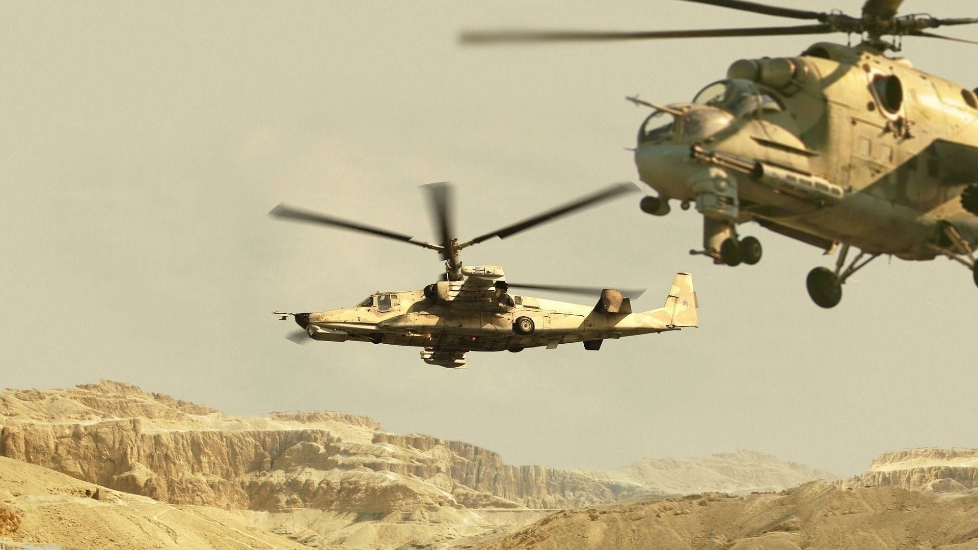 Helicopter 桌布 壁紙 — 兩架軍用直升機在朦朧的天空下低飛越過崎嶇的沙漠地形。