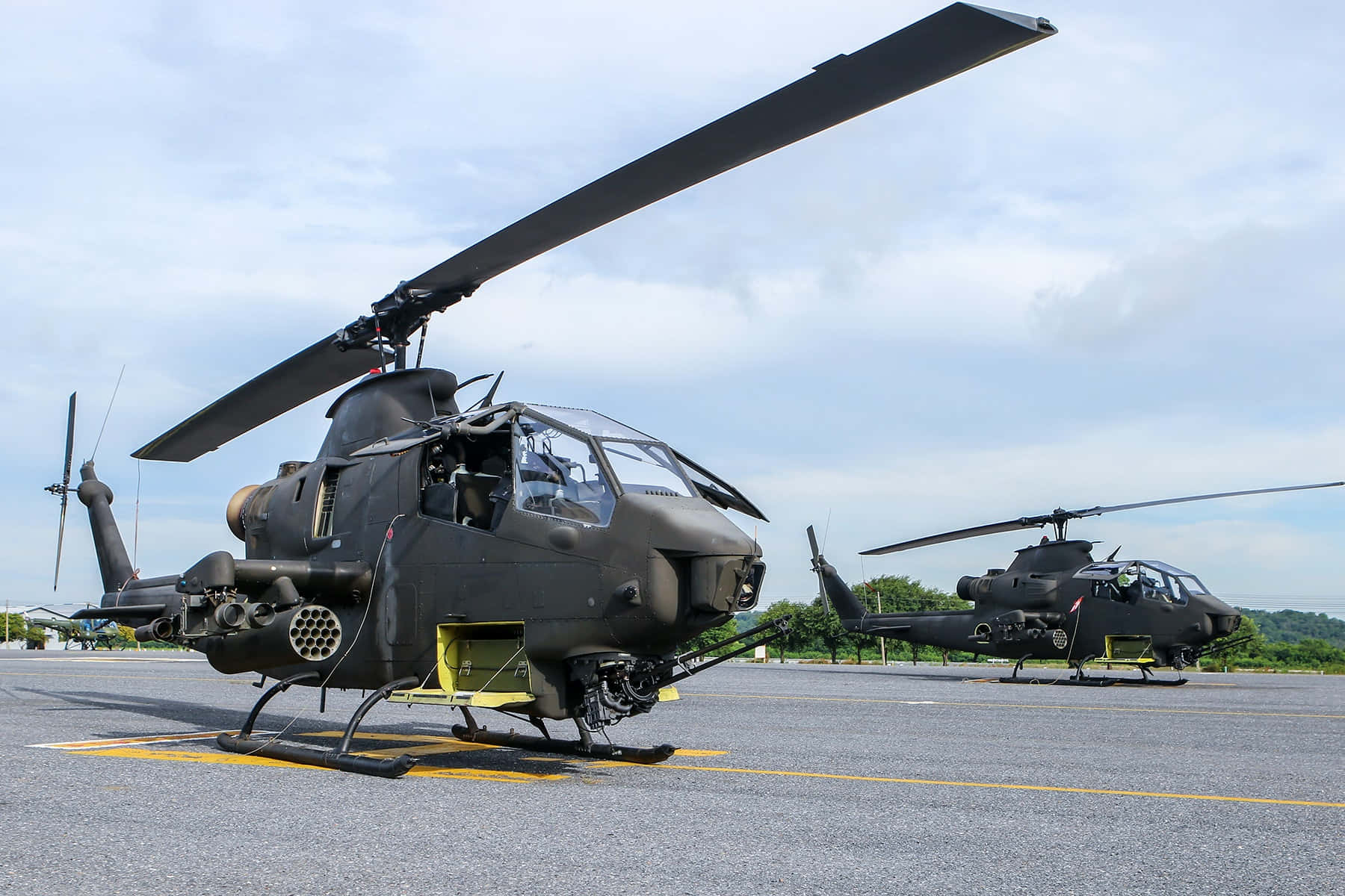 Helicopter 桌布 壁紙 — 兩架黑色軍用直升機停泊在停機坪上，天空多雲，背景是綠色山丘。