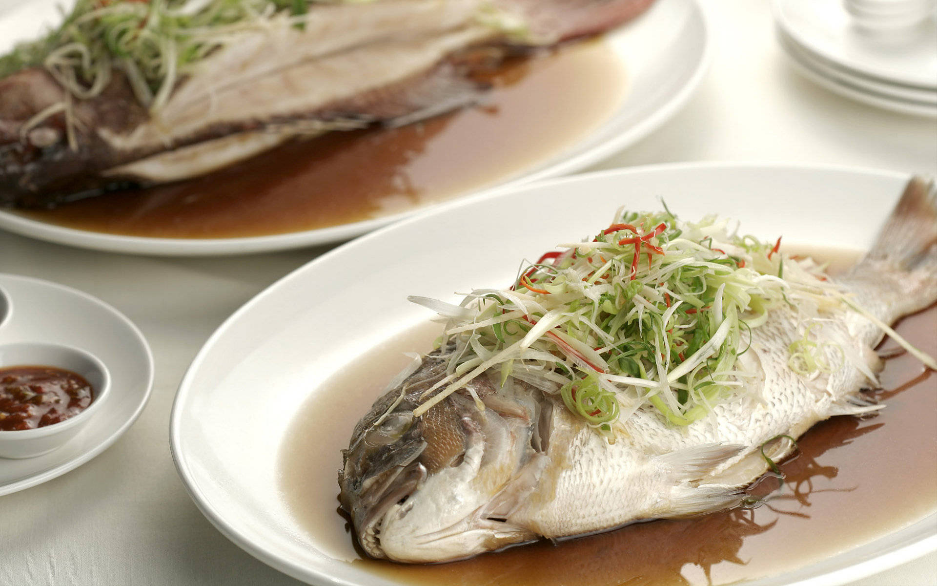 4K Food 桌布 壁紙 — 兩條清蒸全魚，配上蔥絲和紅辣椒絲，放在白色盤子上，淋上美味醬汁。