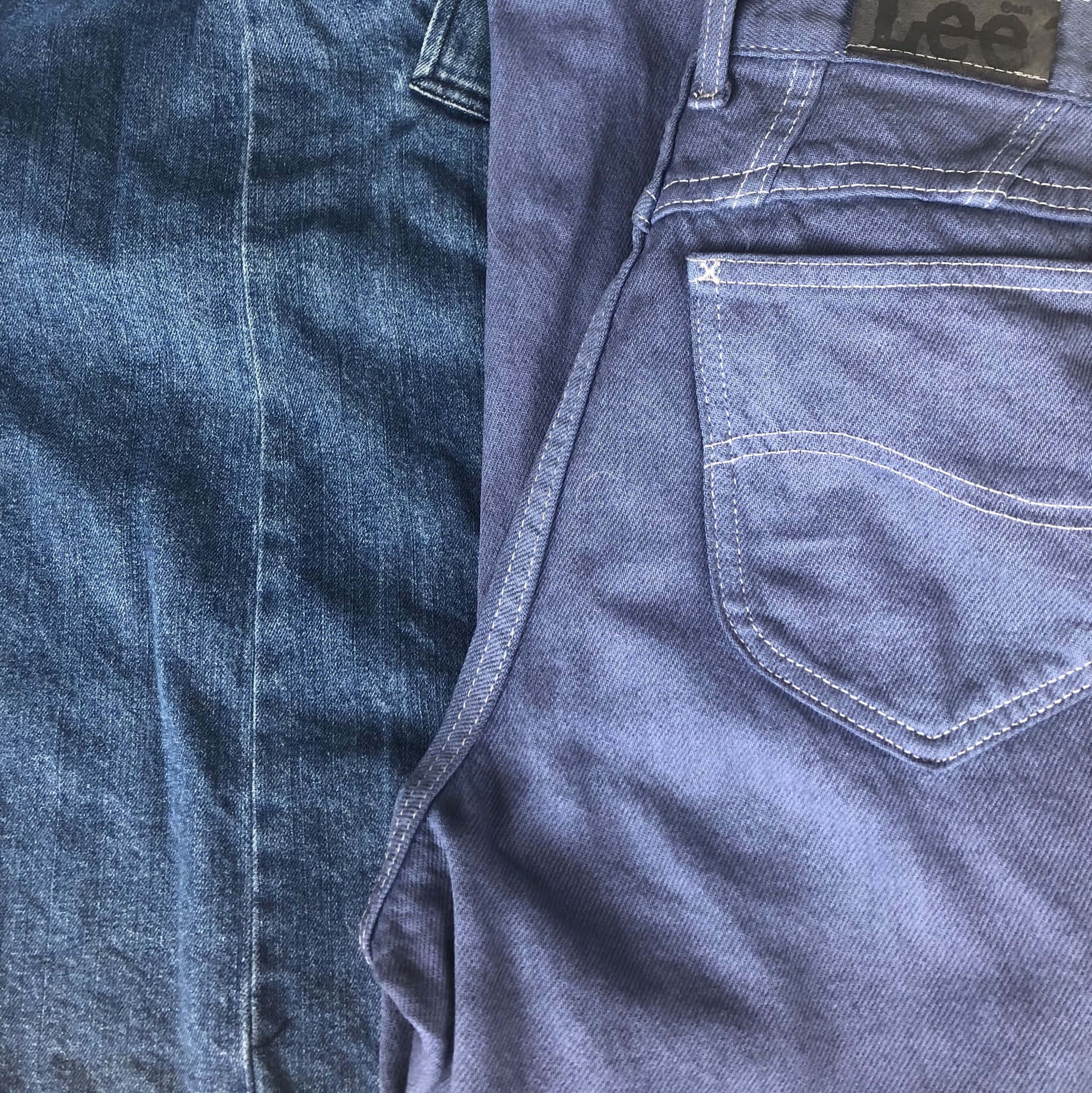 Denim Blue 桌布 壁紙 — 兩條藍色牛仔褲的特寫，顯示後袋的縫線細節和品牌標籤。