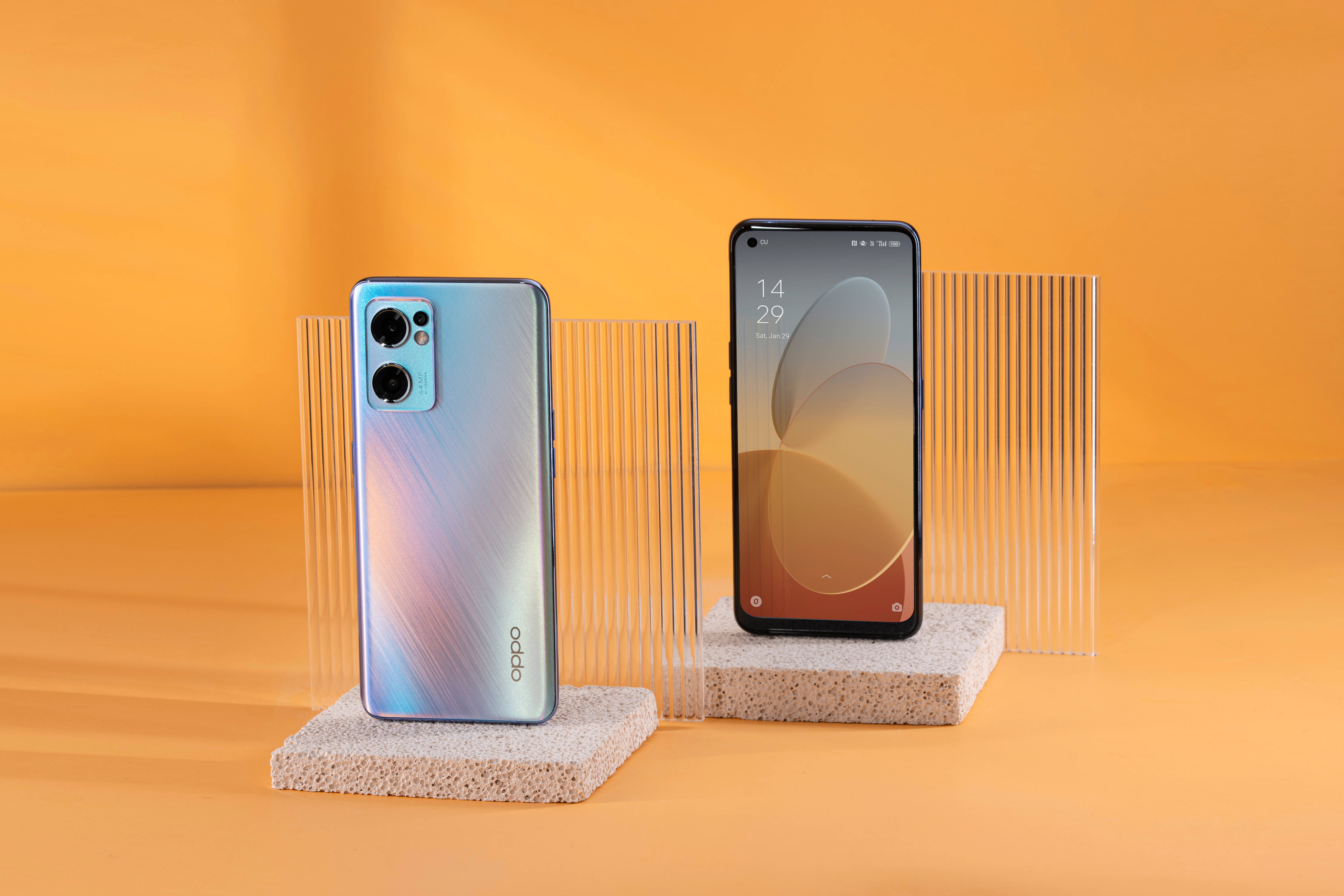 oppo 桌布 壁紙 — 兩款時尚的OPPO智慧型手機展示在紋理石質底座上，背景為溫暖的橙色漸變。