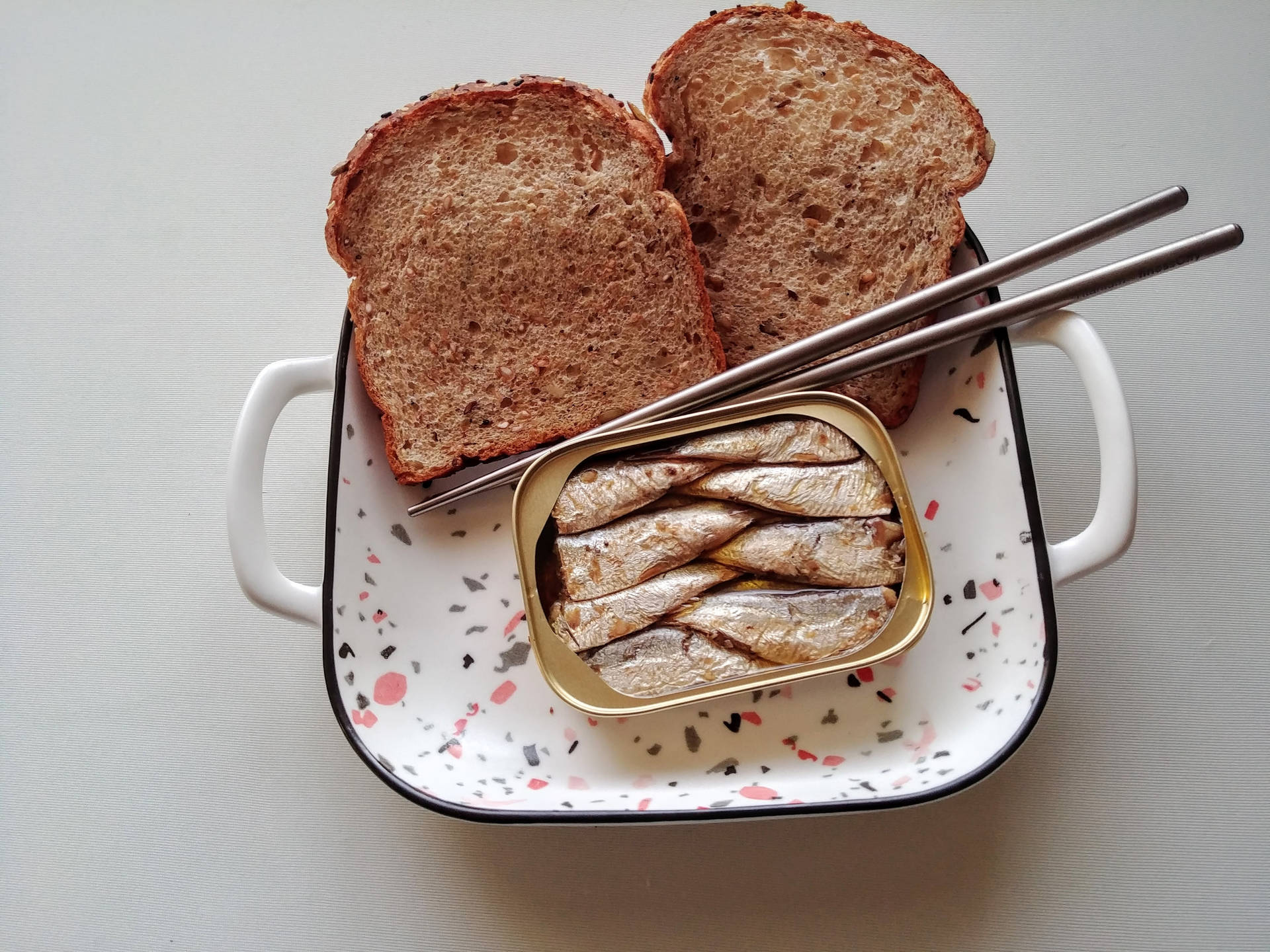 魚 桌布 壁紙 — 兩片全麥麵包和一罐沙丁魚放在帶有斑點的陶瓷盤上，配以筷子。